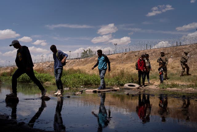 <p>Migrants go back across the Rio Grande at Ciudad Juárez on 13 May after Texas National Guard members tell them to leave the spot where they had gathered under the Ysleta-Zaragoza Bridge at El Paso in hopes of surrendering themselves to seek asylum in the United States</p>