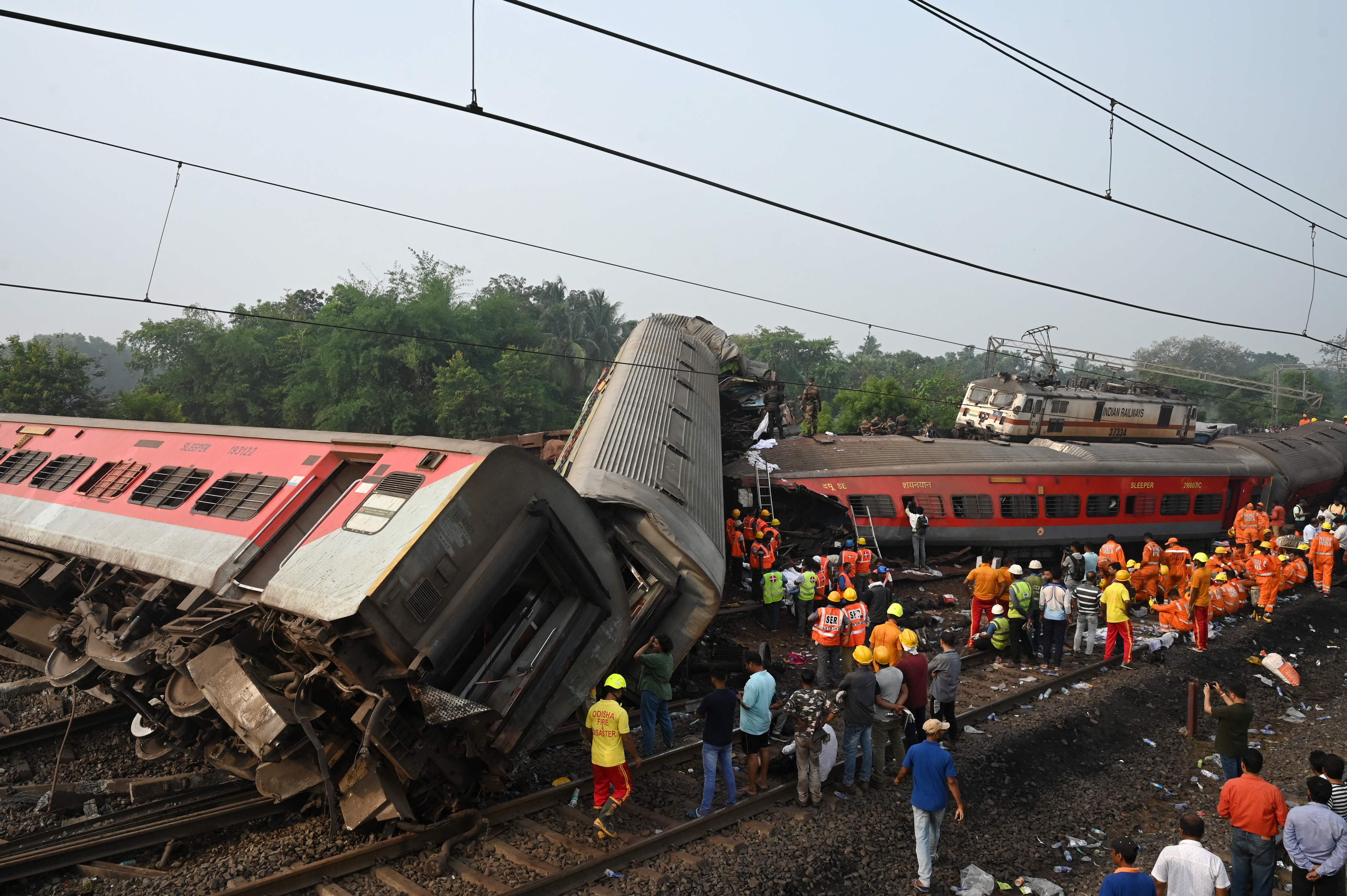 Rescue workers gather around damaged carriages during search for survivors at the accident site of a three-train collision near Balasore