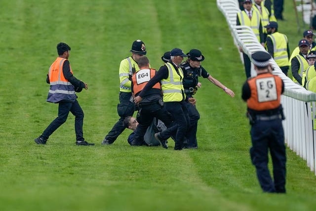 <p>A protester runs onto the course and is tackled to the ground on Derby Day at Epsom Downs Racecourse </p>