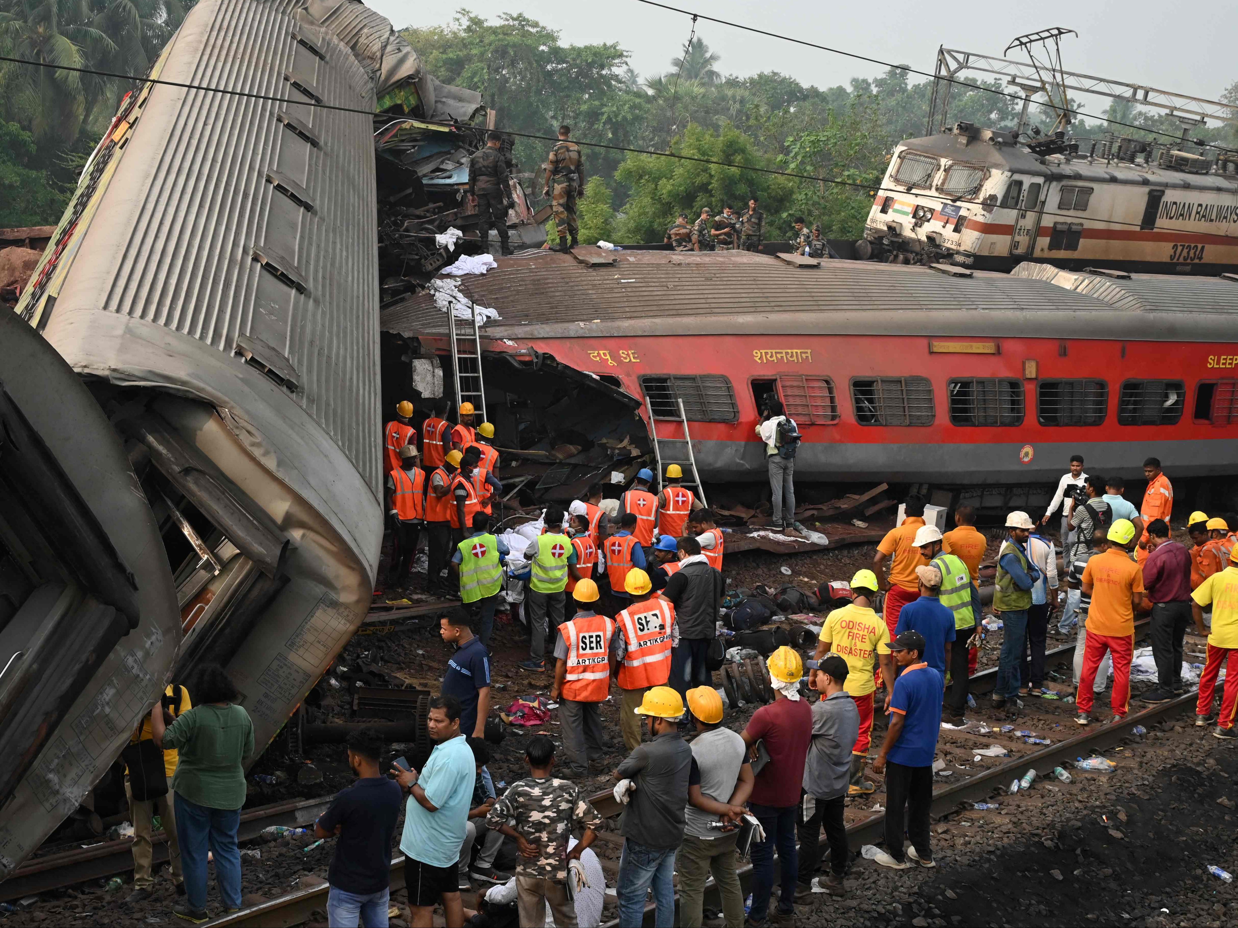Rescue workers gather around damaged carriages at the accident site of a three-train collision near Balasore