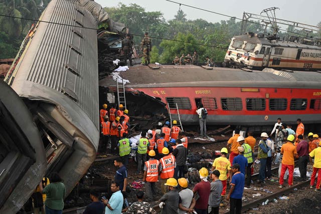 <p>Rescue workers gather around damaged carriages at the accident site of a three-train collision near Balasore</p>