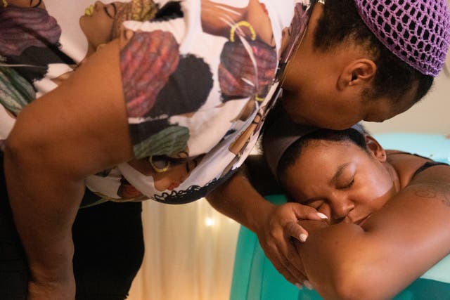 <p>Holistic doula Ciara Clark receives a kiss from her mother Elle while in her home birthing pool</p>