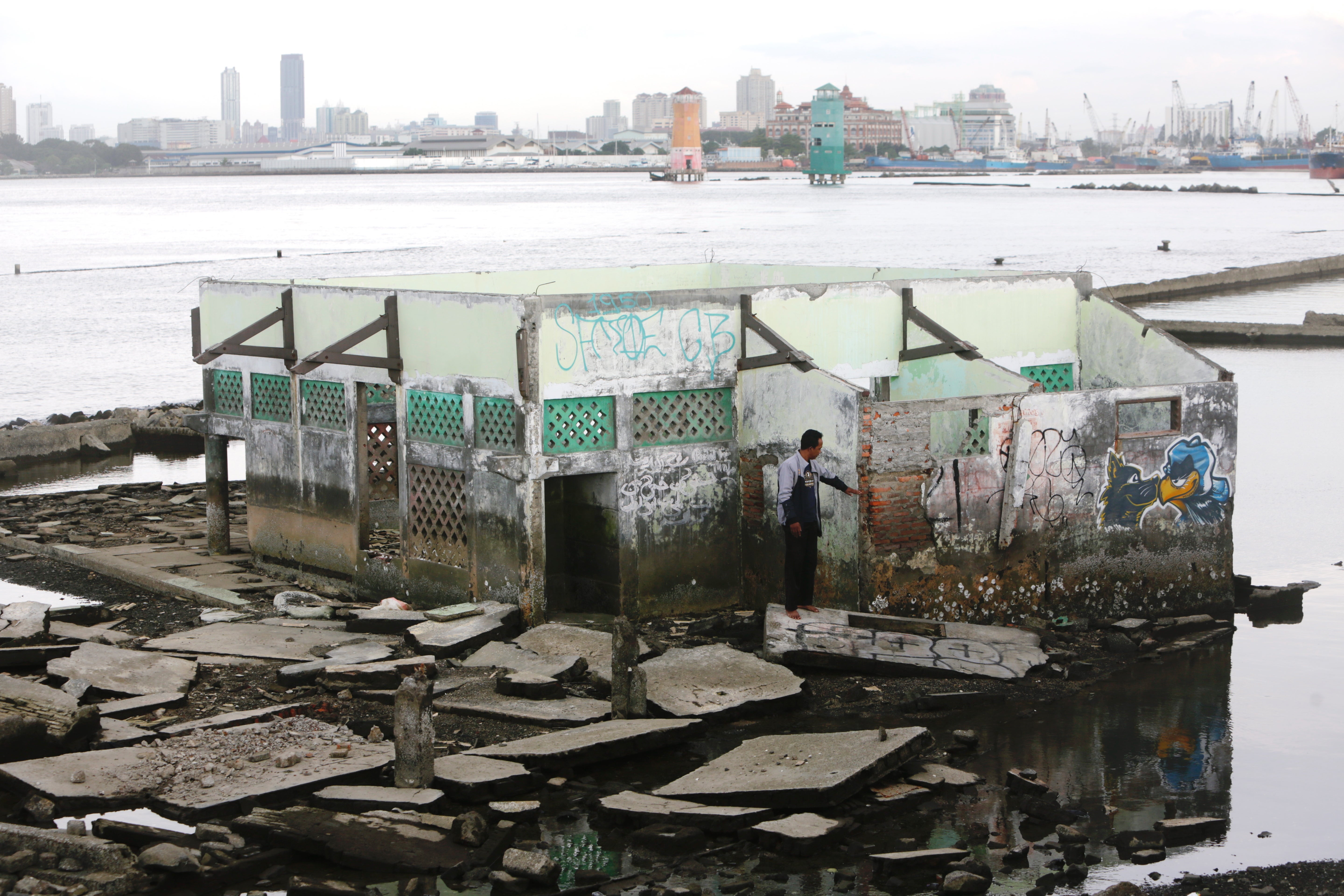 Jumadi Guthafsitom walks around the abandoned Waladuna mosque that has been sinking due to rising seawater and land erosion on Jakarta’s northern coast