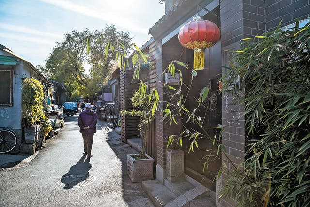 <p>A pedestrian strolls through a <em>hutong</em> in Beijing</p>