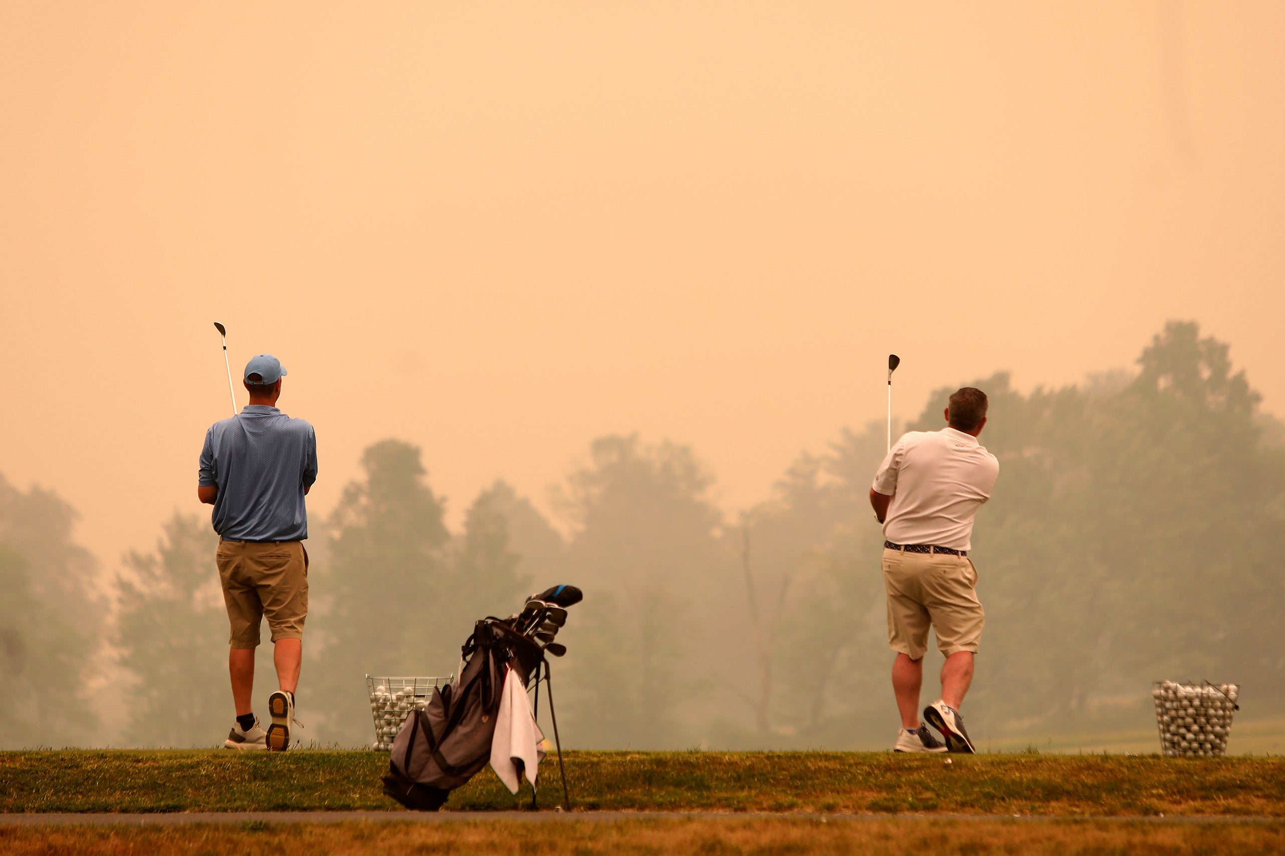 Golfers watch their shots at the driving range at Valley Country Club in Sugarloaf, Pennsylvania as smoke from wildfires in Canada fill the air on Wednesday