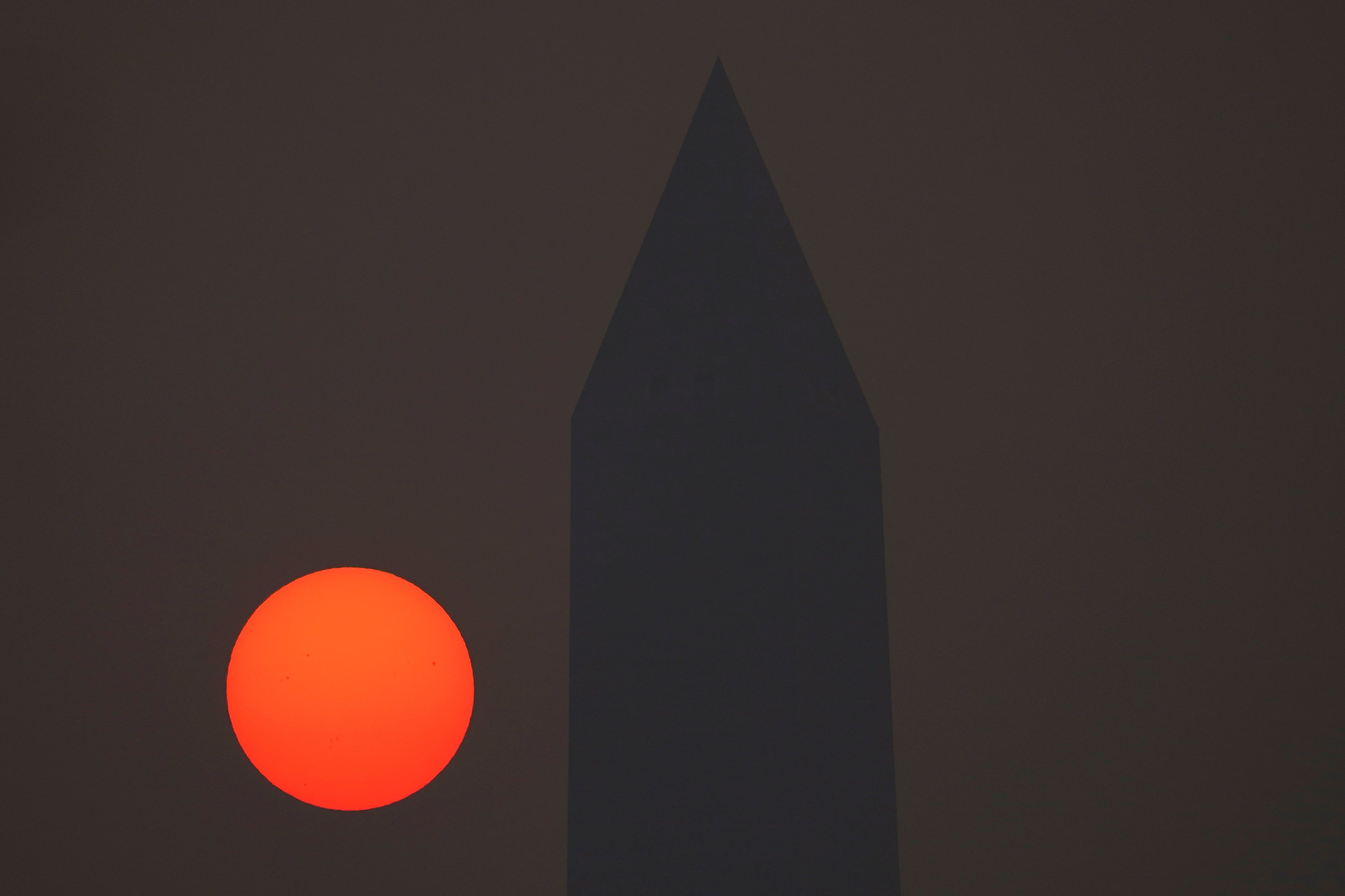 The sun rises behind the Washington Monument shrouded in a thick layer of smoke on Thursday in DC