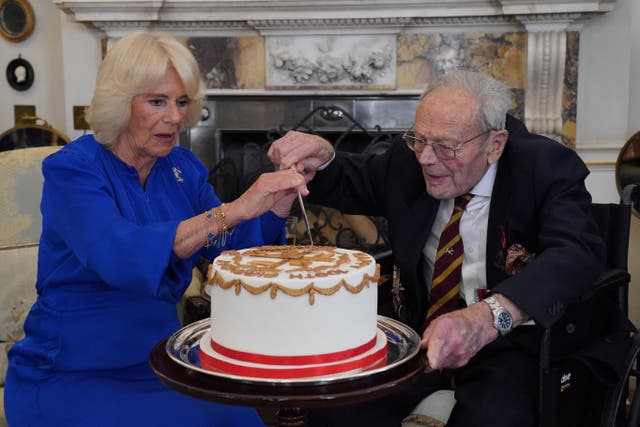 Queen Camilla helps Michael de Burgh cut a cake to celebrate his forthcoming birthday (Jonathan Brady/PA)