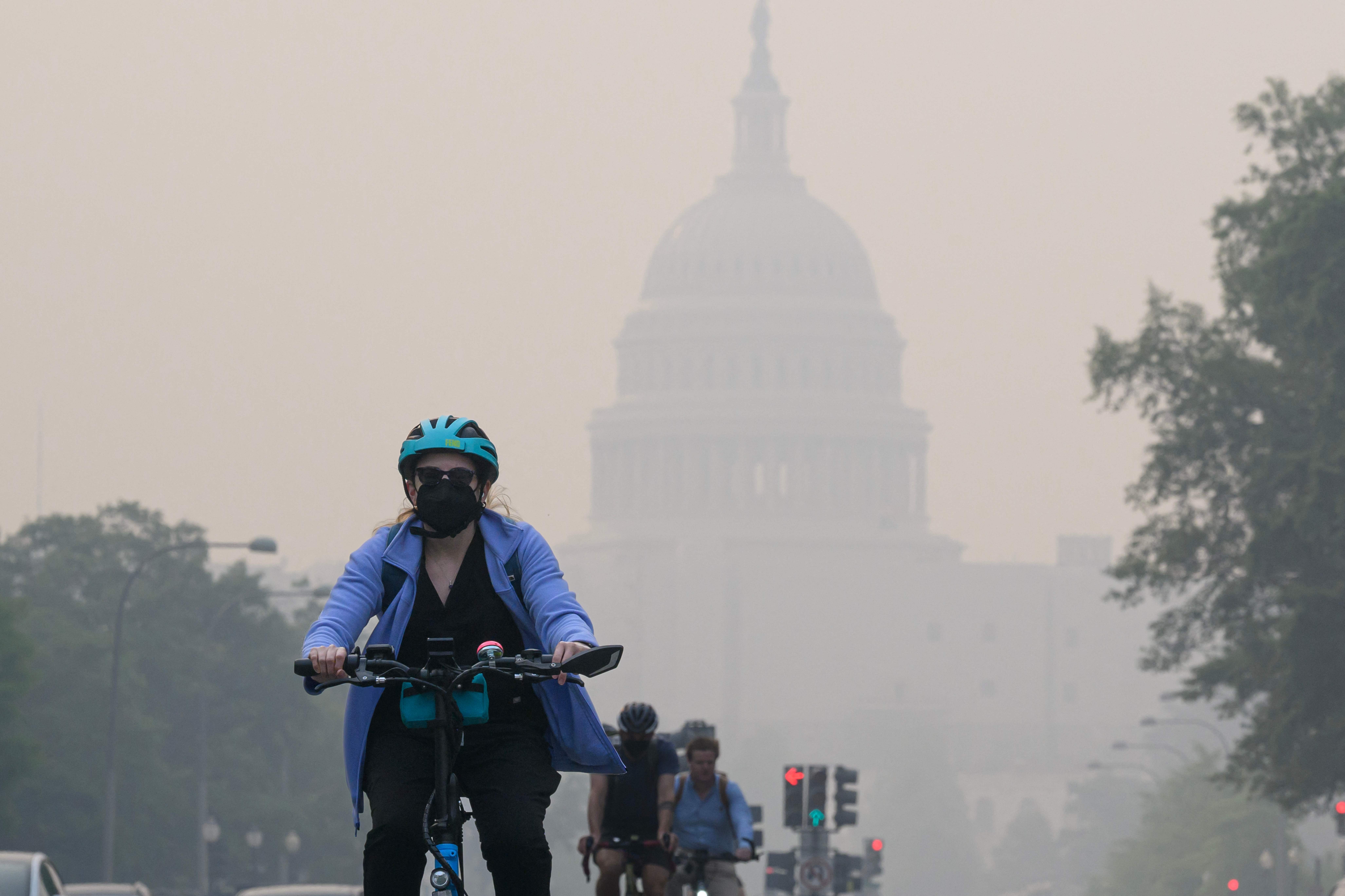A cyclist rides under a blanket of haze partially obscuring the US Capitol in Washington, DC, on Thursday