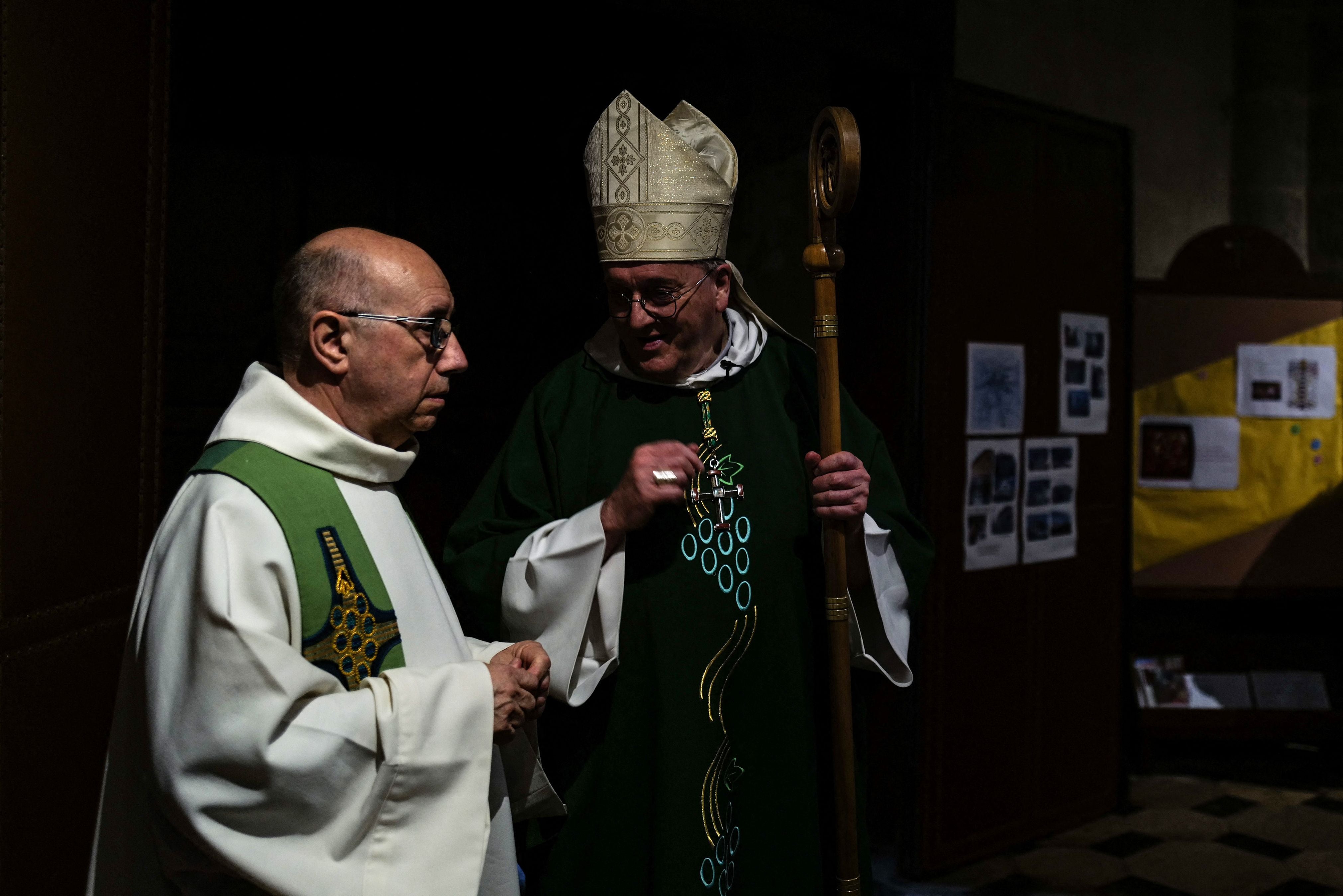 Father Didier Milani (L) speaks with Bishop Yves Le Saux (C) ahead of mass