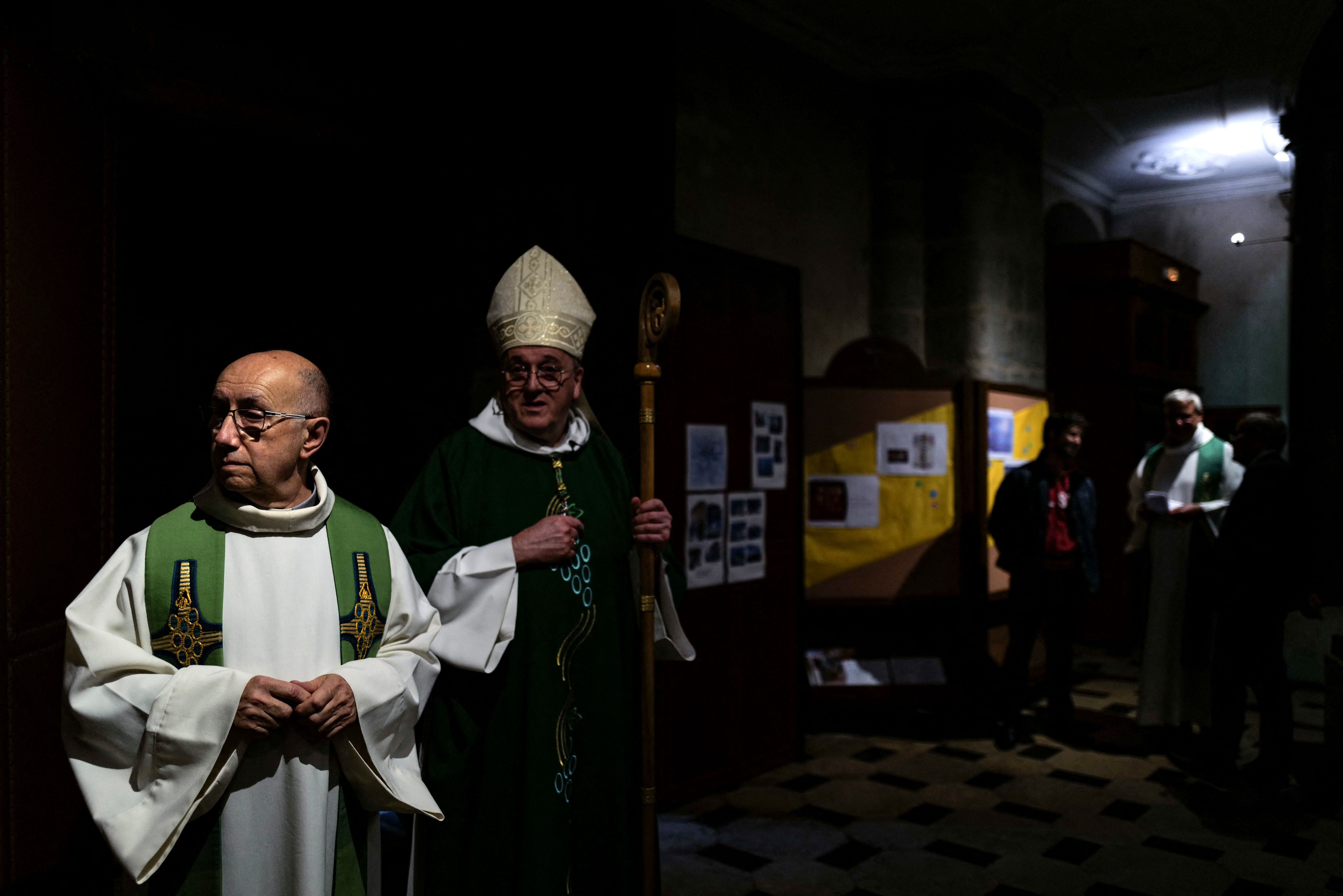 Father Didier Milani (L) speaks with Bishop Yves Le Saux (C) ahead of mass