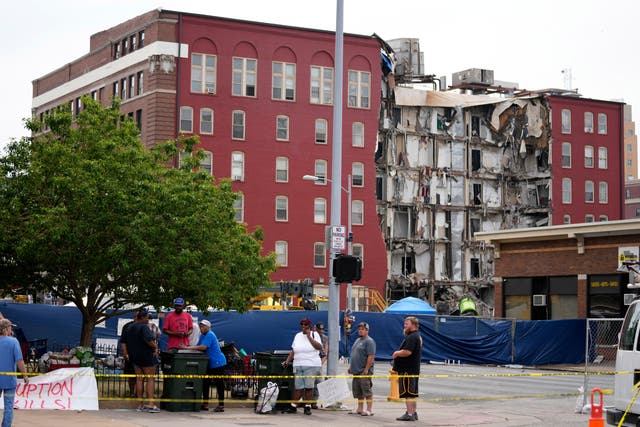 <p>Local residents stand on a sidewalk near a collapsed apartment building, Monday, June 5, 2023, in Davenport, Iowa. The six-story, 80-unit building partially collapsed May 28. (AP Photo/Charlie Neibergall)</p>