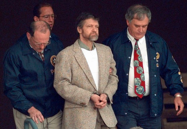 <p>Ted Kaczynski flanked by federal agents in 1996 </p>