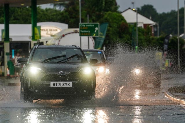 Vehicles are driven through flash flooding in the Lower Wick area of Worcester (David Davies/PA)