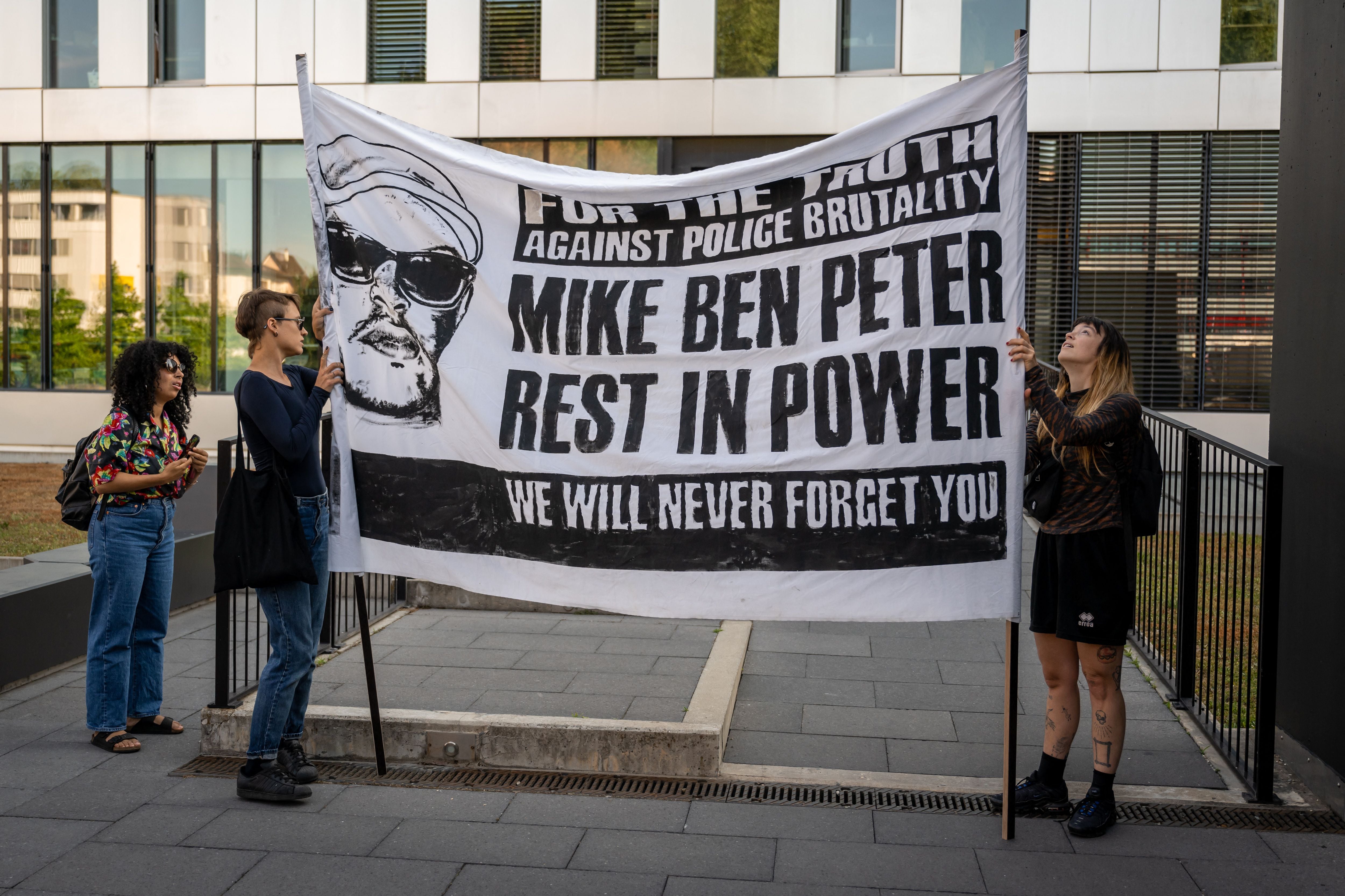 Activists hold a banner prior to opening of the trial of six policemen accused on homicide charges in relation to the death of 39-year-old Nigerian Mike Ben Peter, in Renens on 12 June 2023