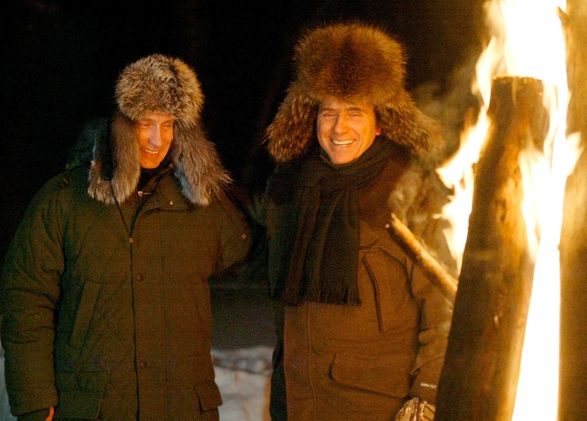 Russian President Vladimir Putin and Italian Prime Minister Silvio Berlusconi smile as they stand near a huge fire in a wildlife preserve and recreation area near a residence of Zavidovo, north-west of Moscow in February, 2003