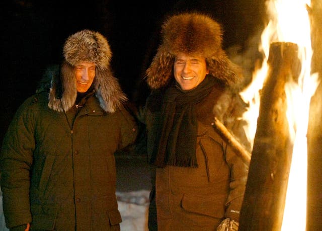 <p>Russian President Vladimir Putin and Italian Prime Minister Silvio Berlusconi smile as they stand near a huge fire in a wildlife preserve and recreation area near a residence of Zavidovo, north-west of Moscow in February, 2003</p>