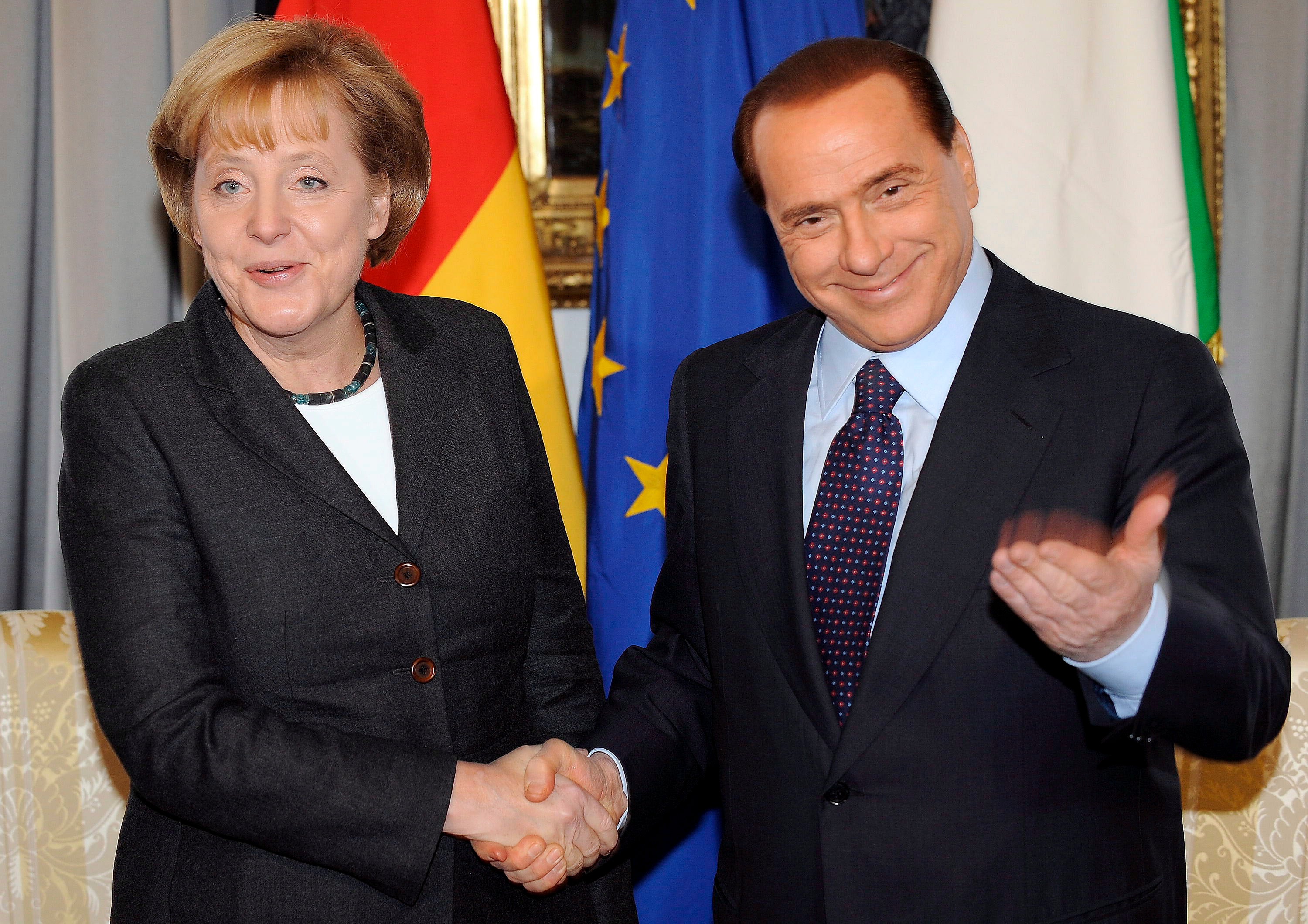 Berlusconi and German chancellor Angela Merkel shake hands during the 2008 Italy-Germany summit in Trieste