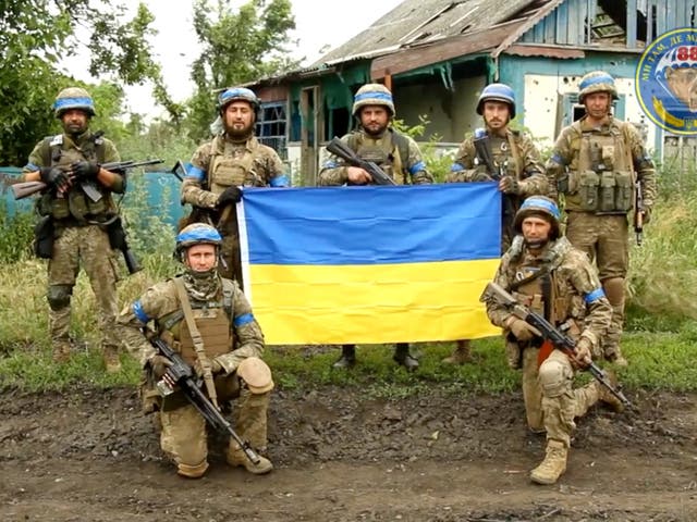 <p>Ukrainian servicemen pose for a photograph with the Ukrainian flag in the liberated village of Storozheve in the Dontesk region</p>