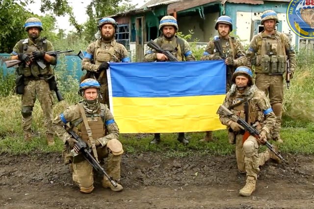 <p>Ukrainian servicemen pose for a photograph with the Ukrainian flag in the liberated village of Storozheve in the Dontesk region</p>