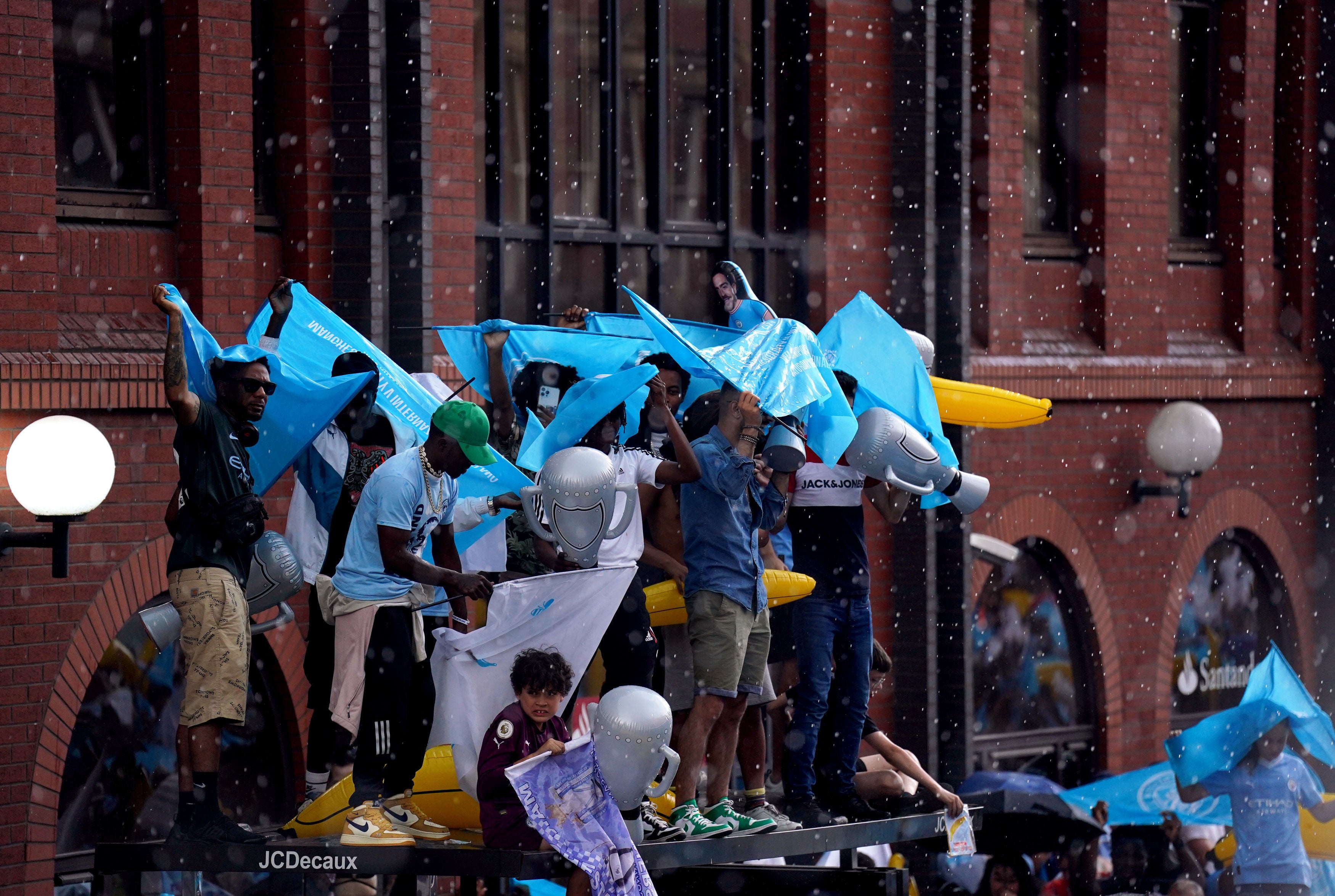 pManchester City fans take shelter from the rain ahead of the Treble Parade in Manchester./p