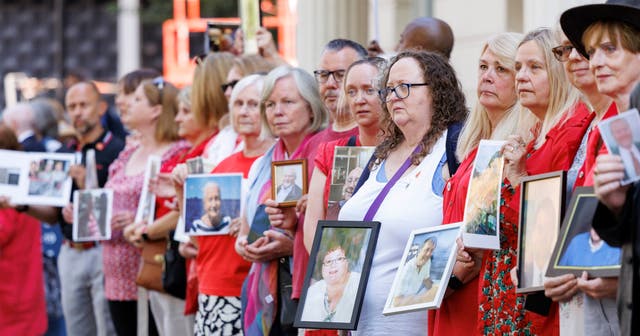 <p>People hold pictures of loved ones lost during the pandemic outside the UK Covid-19 Inquiry at Dorland House in London</p>