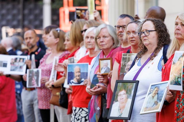 <p>People hold pictures of loved ones lost during the pandemic outside the UK Covid-19 Inquiry at Dorland House in London</p>