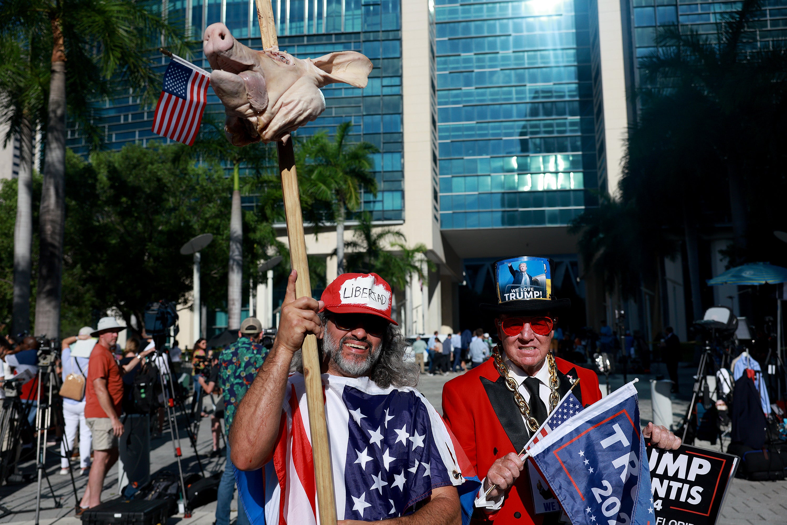 Osmany Estrada (L) holds a pigs head as he and Gregg Donovan gather outside the Wilkie D. Ferguson Jr. United States Federal Courthouse