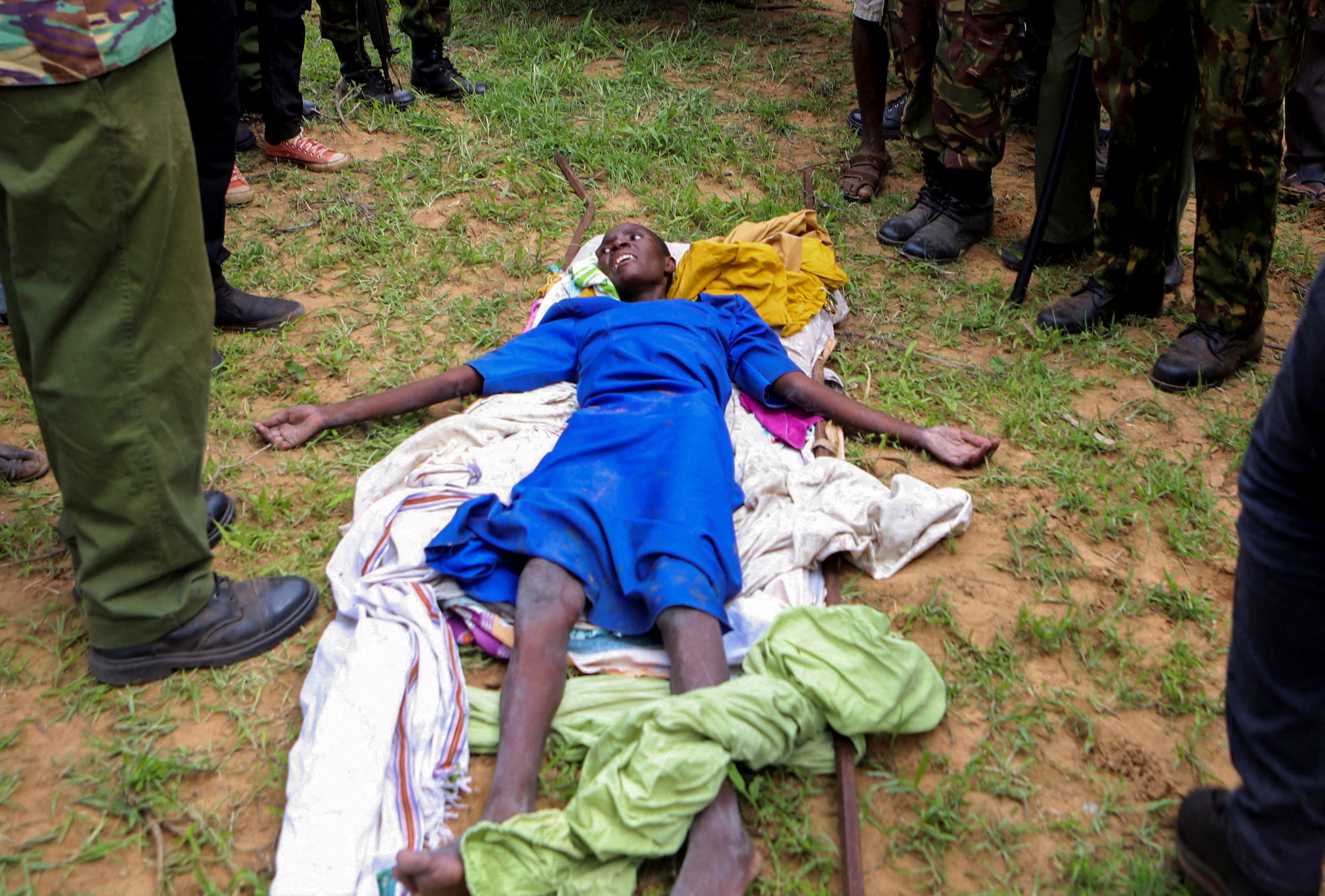 An emaciated member of a Christian cult named as Good News International Church, whose members believed they would go to heaven if they starved themselves to death, is guarded by Kenya police officers and officials from the civil society in Shakahola forest on 23 April
