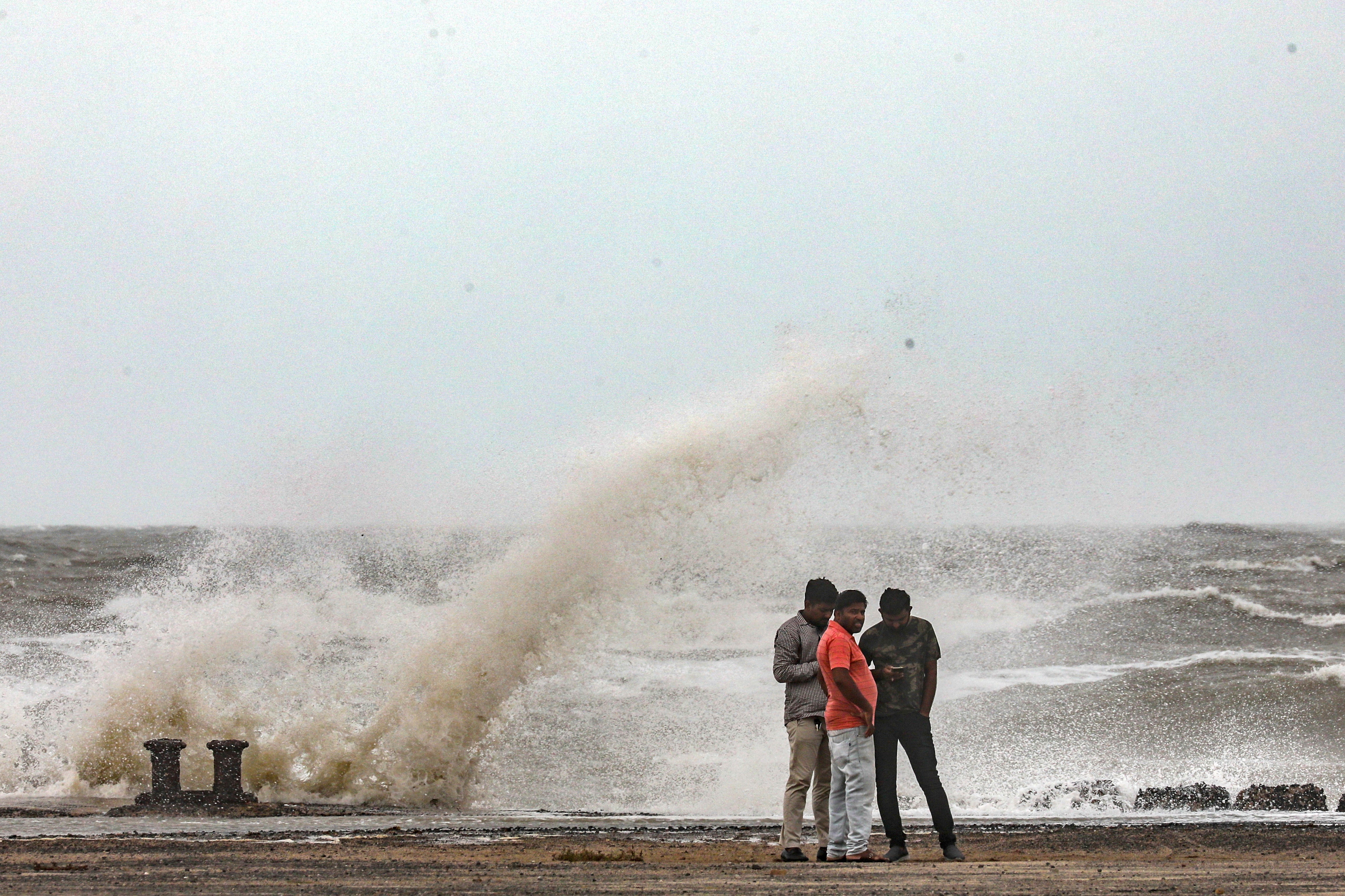 People stand near the coast during high tide in Mandvi, in the Kutch district of the western state of Gujarat, India