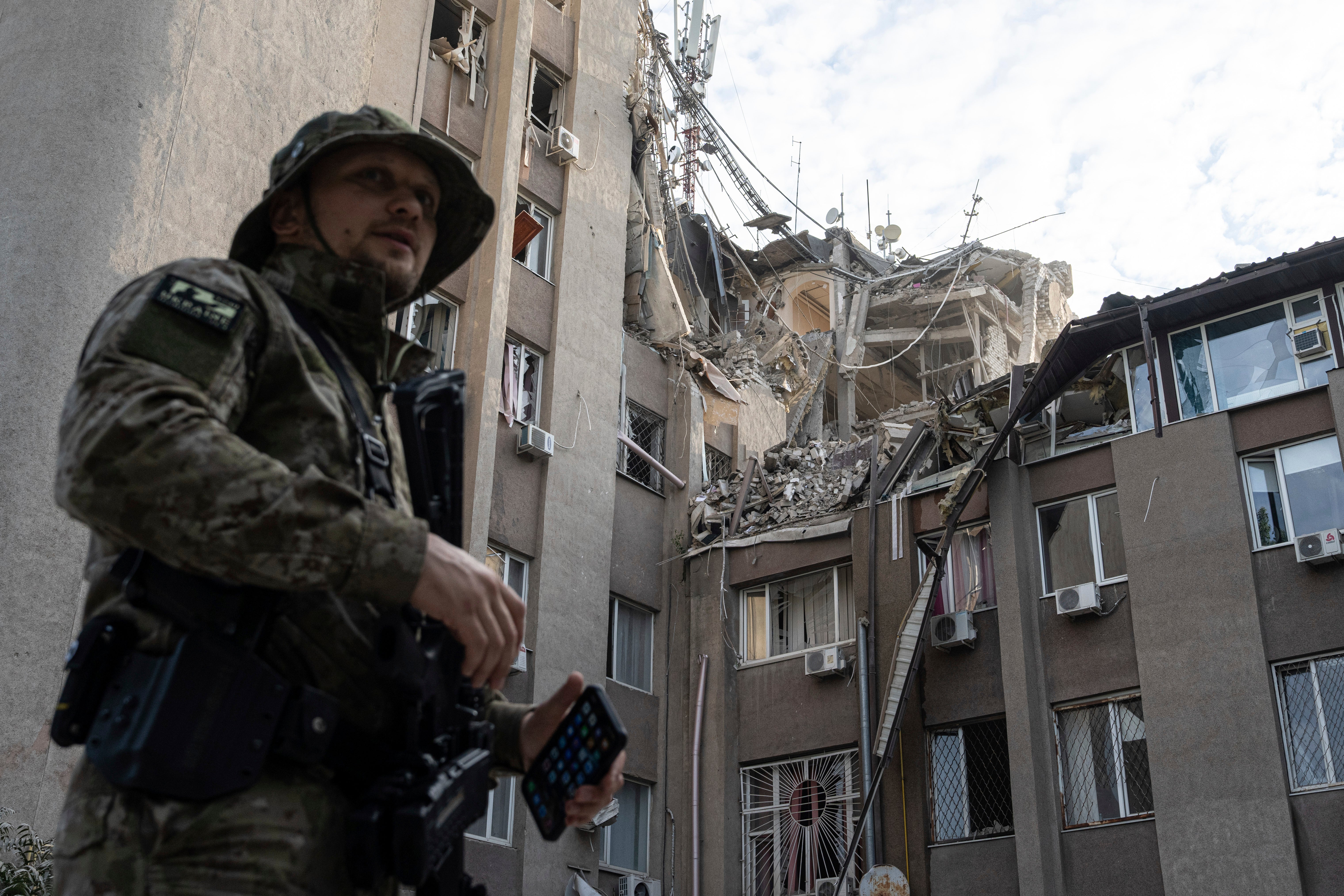 A Ukrainian serviceman stands in front of a building that has been heavily damaged by a Russian airstrike, in Kherson on Thursday