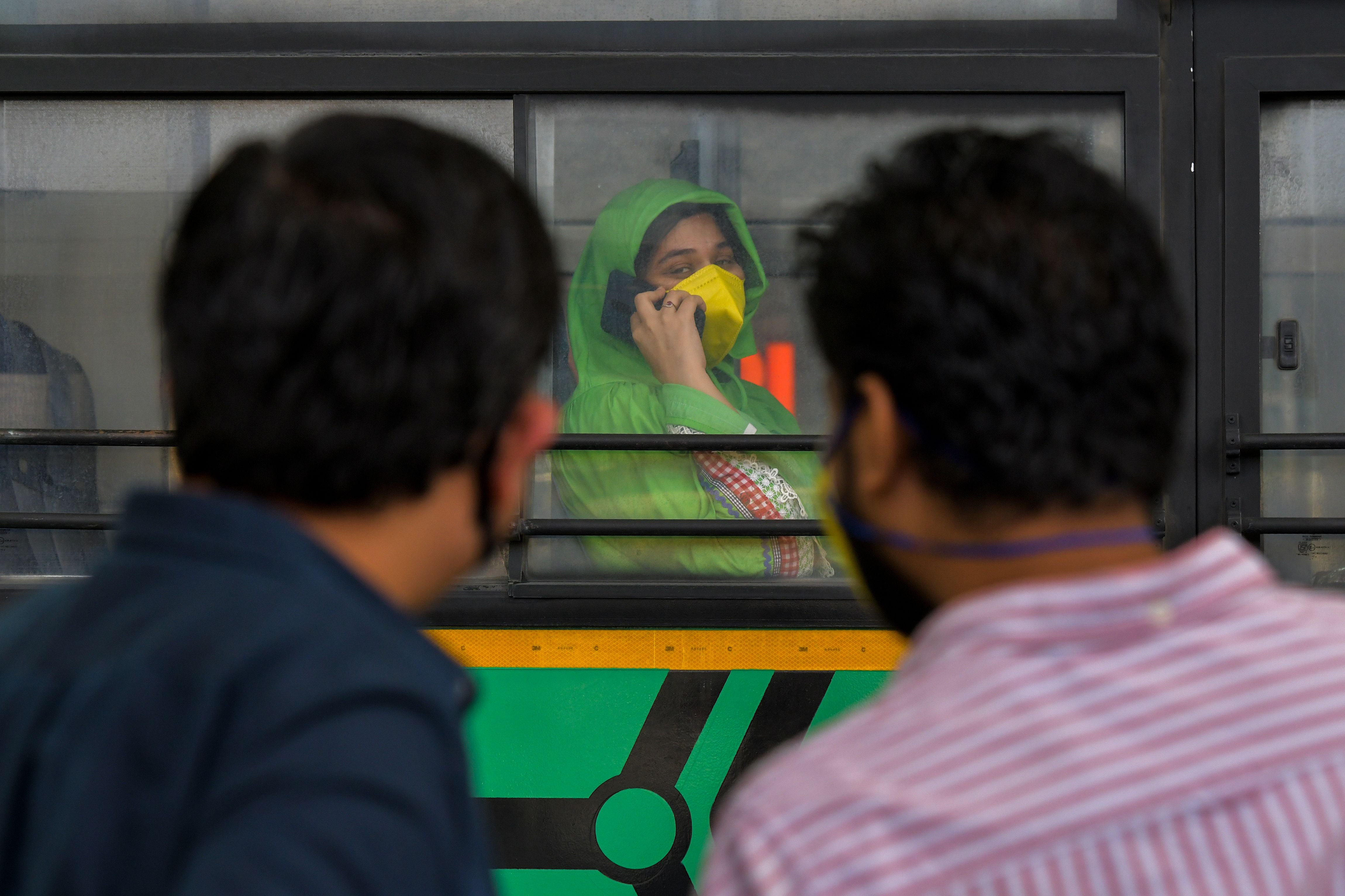 A woman (centre) speaks on her phone on a bus at the Bengaluru International Airport