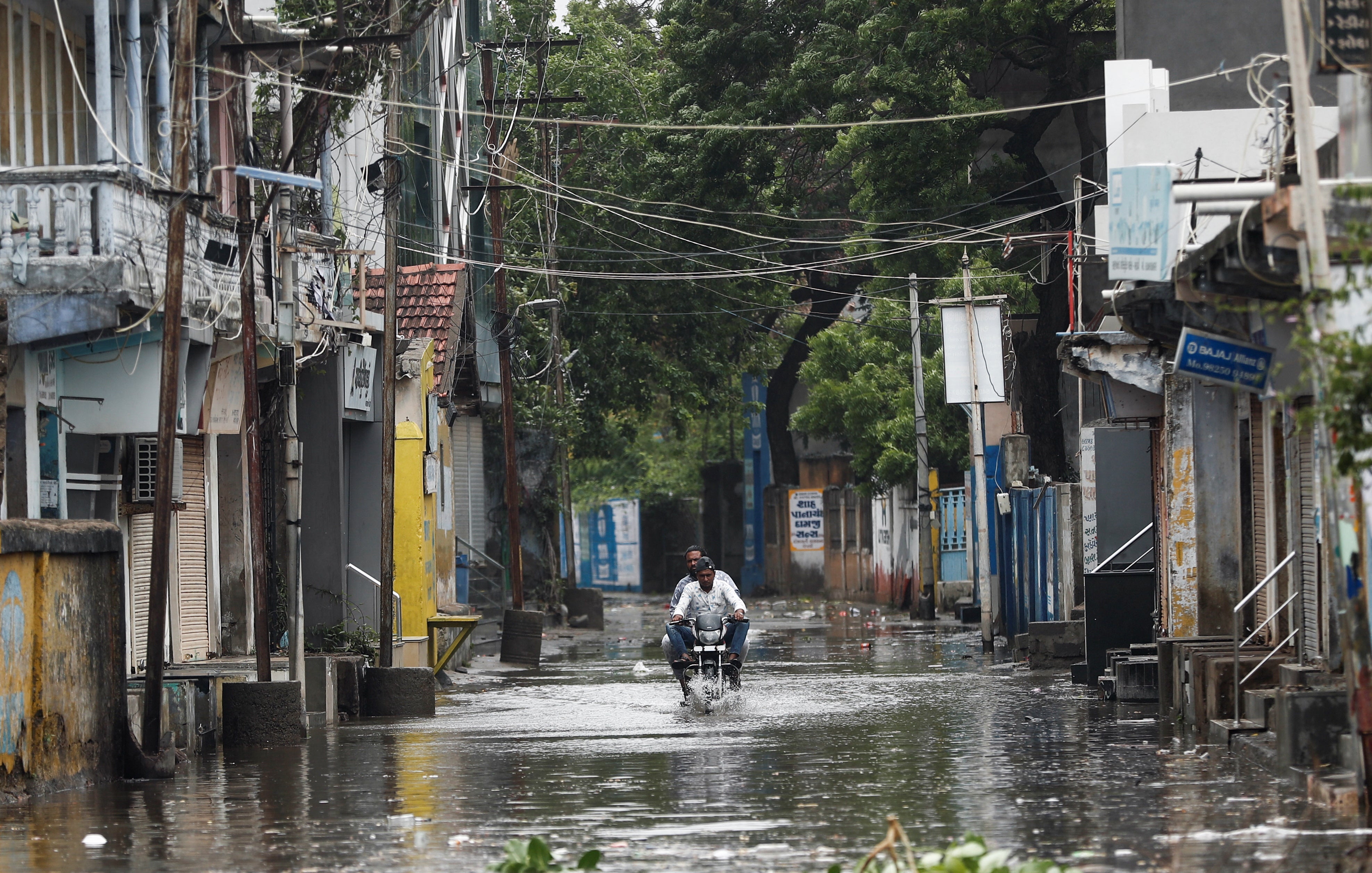 A man rides a motorcycle through a waterlogged street in Mandvi before the arrival of cyclone Biparjoy in the western state of Gujarat, India
