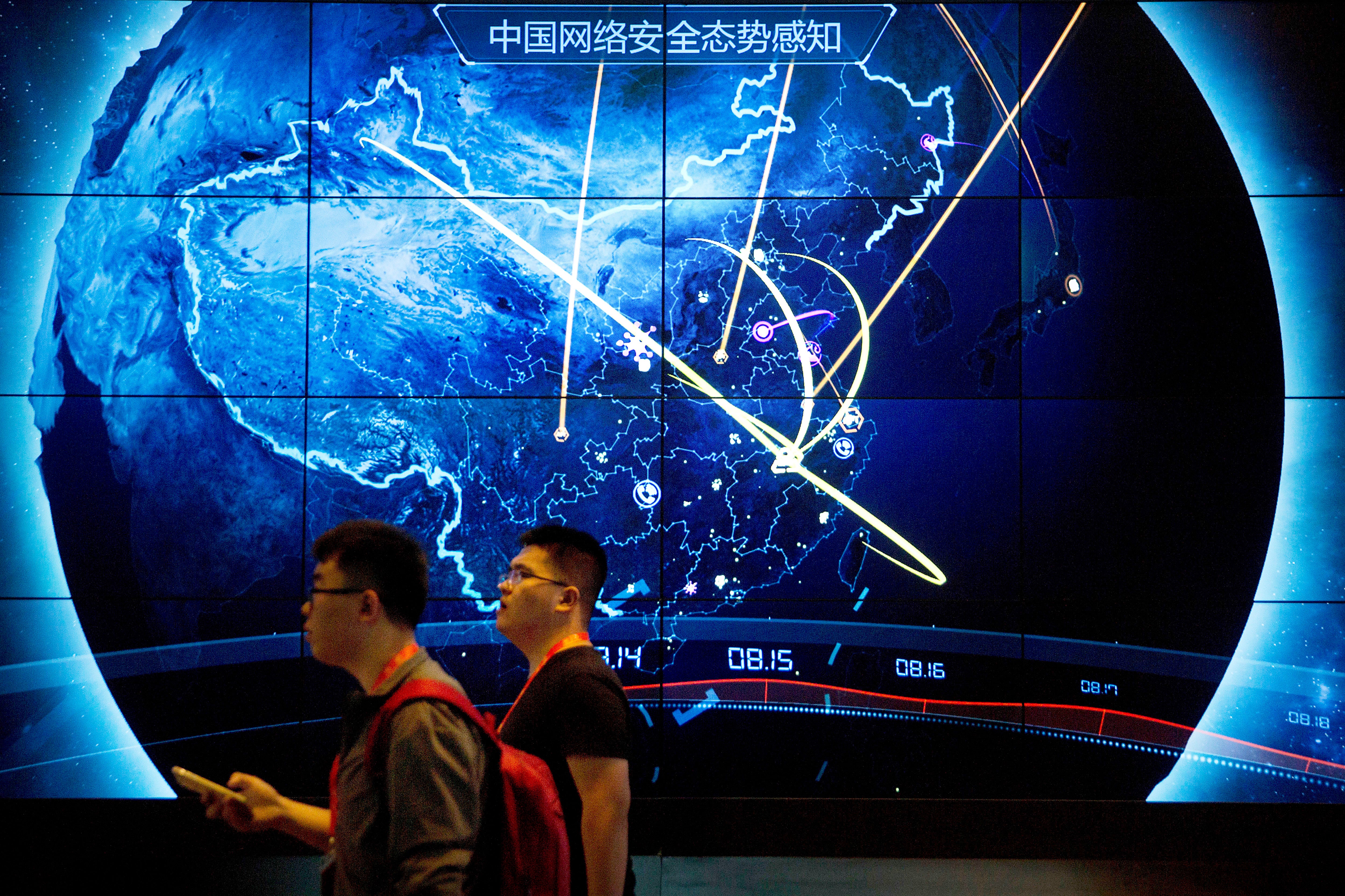 Attendees at a Chinese internet safety conference walk past an electronic display showing recent cyberattacks in China