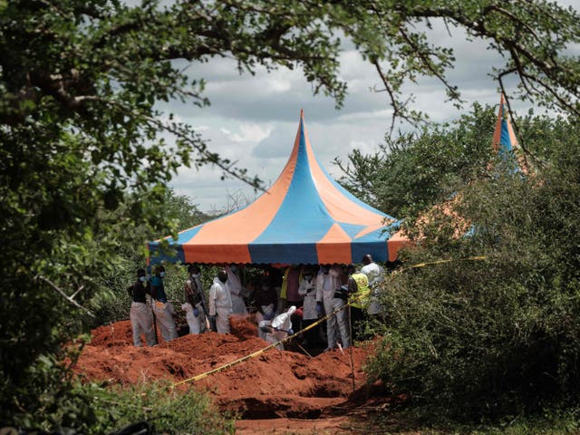 Workers take shelter while digging the ground to exume bodies from the mass grave site in the Shakahola forest of Malindi, Kenya