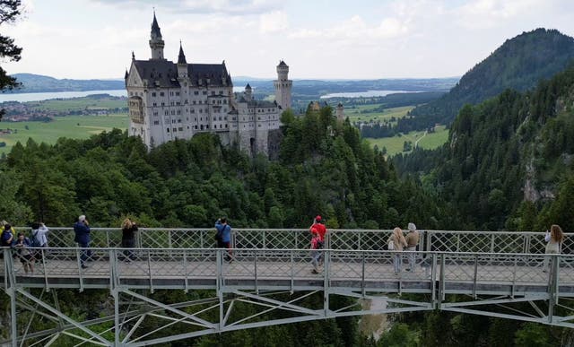 <p>Un grupo de turistas contempla la vista del castillo de Neuschwanstein desde el puente de Marienbrücke</p>