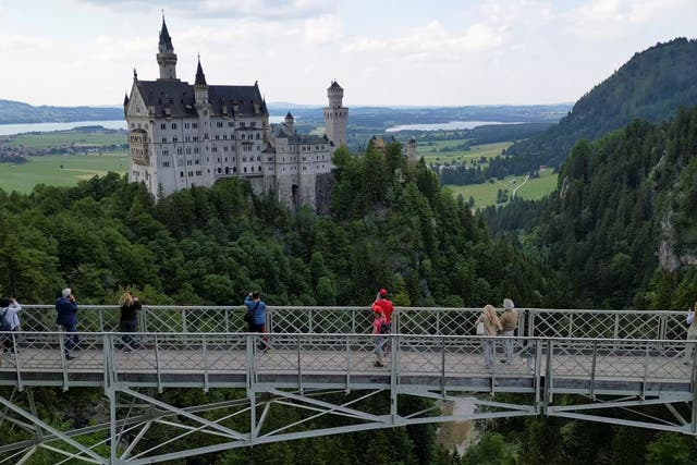 <p>Un grupo de turistas contempla la vista del castillo de Neuschwanstein desde el puente de Marienbrücke</p>