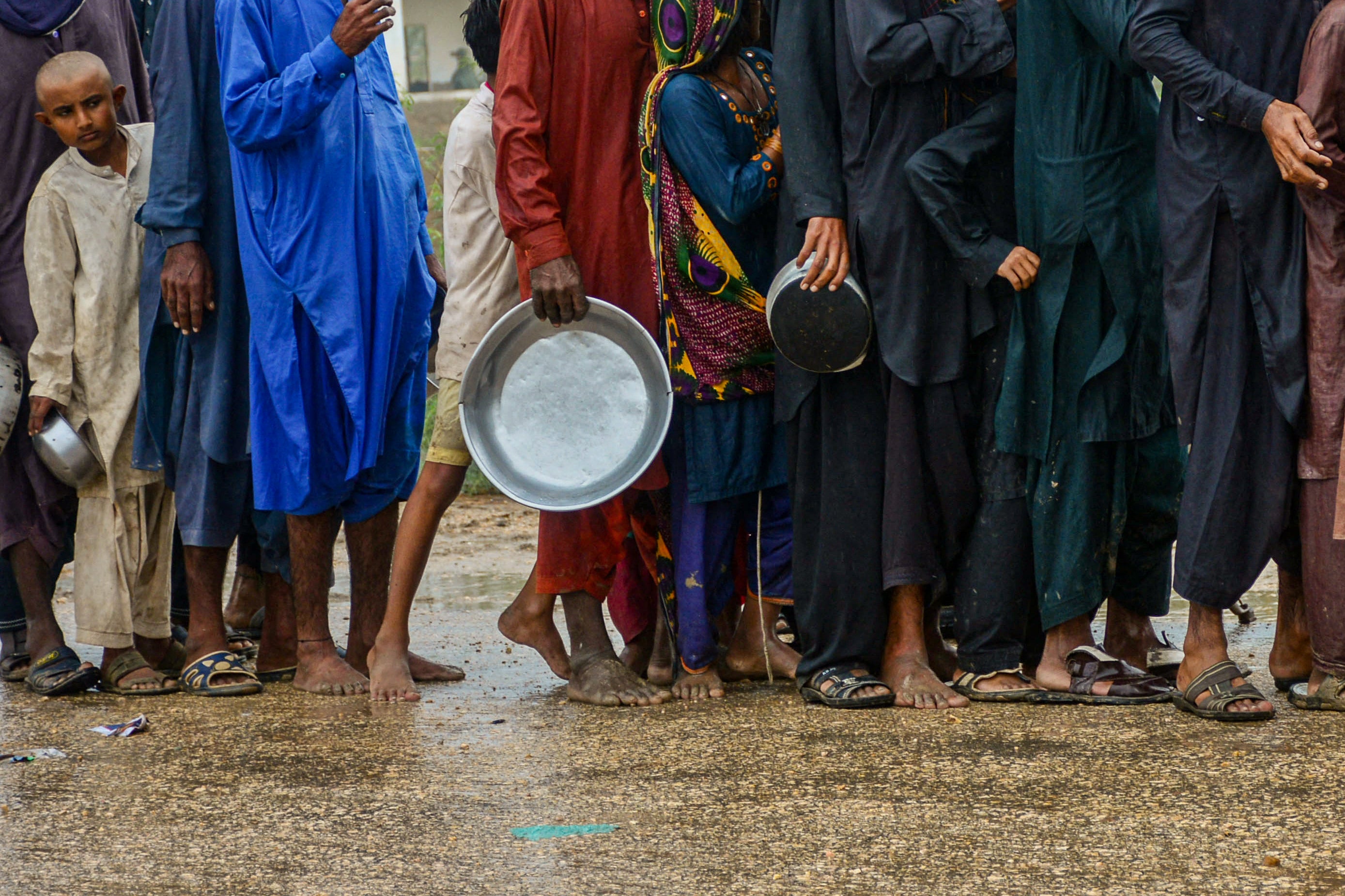 Men and children in Pakistan queue up to receive food near a temporary shelter set at a school in a coastal area in Sujawal, Sindh province