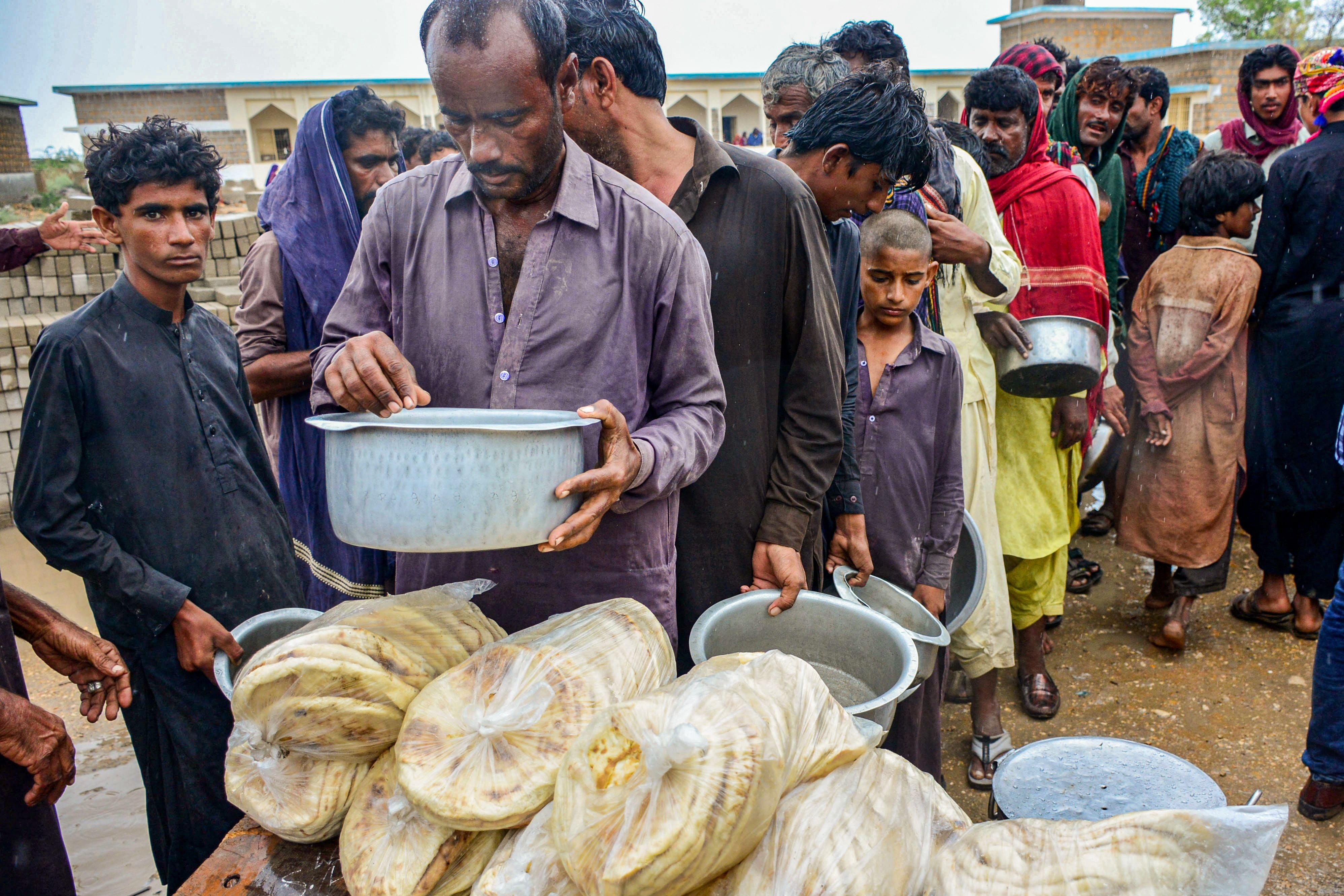 Cyclone evacuees receive food near a temporary shelter set at a school in Pakistan’s coastal area in Sujawal in Sindh province