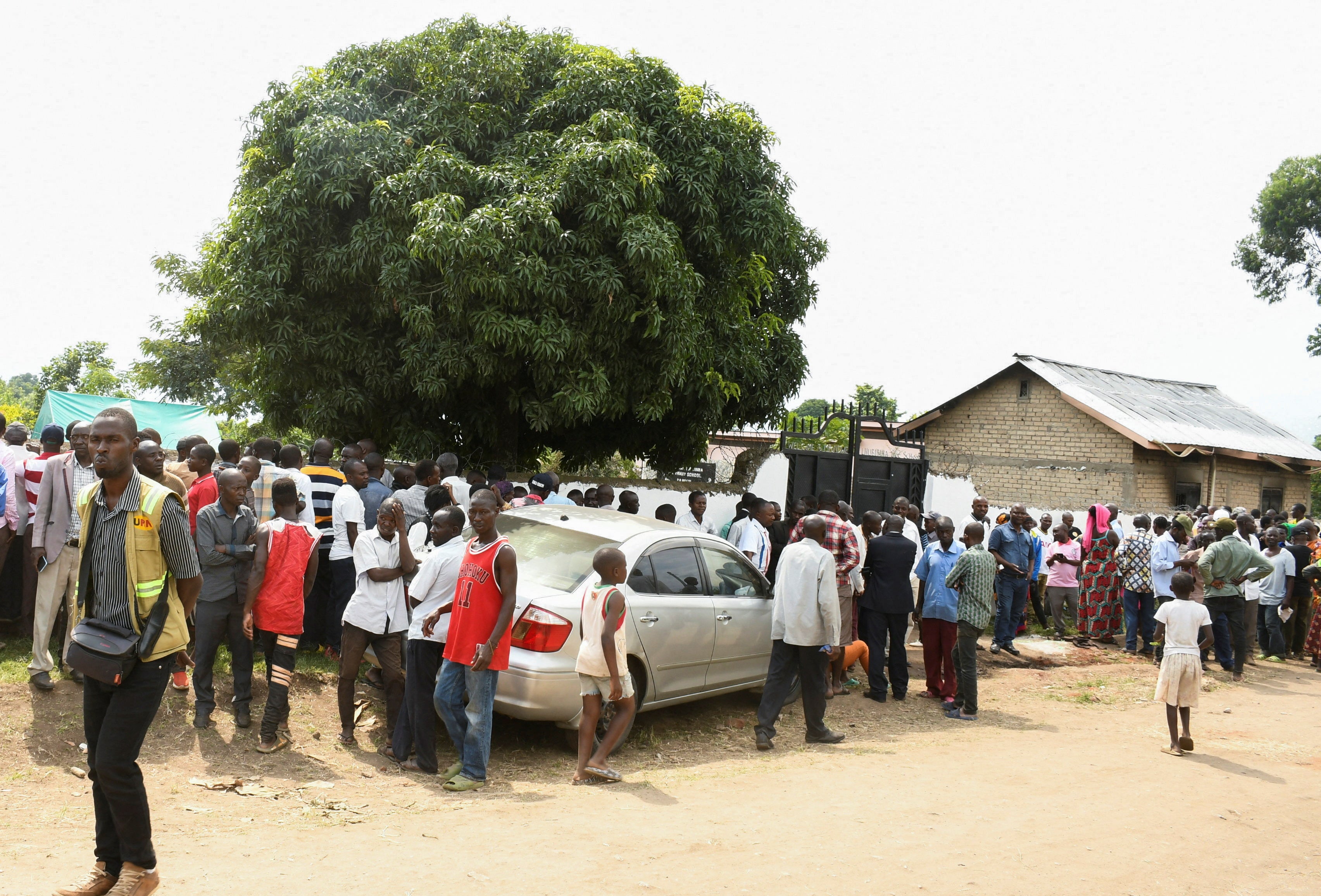 <p>Families wait for news outside the school in Mpondwe </p>