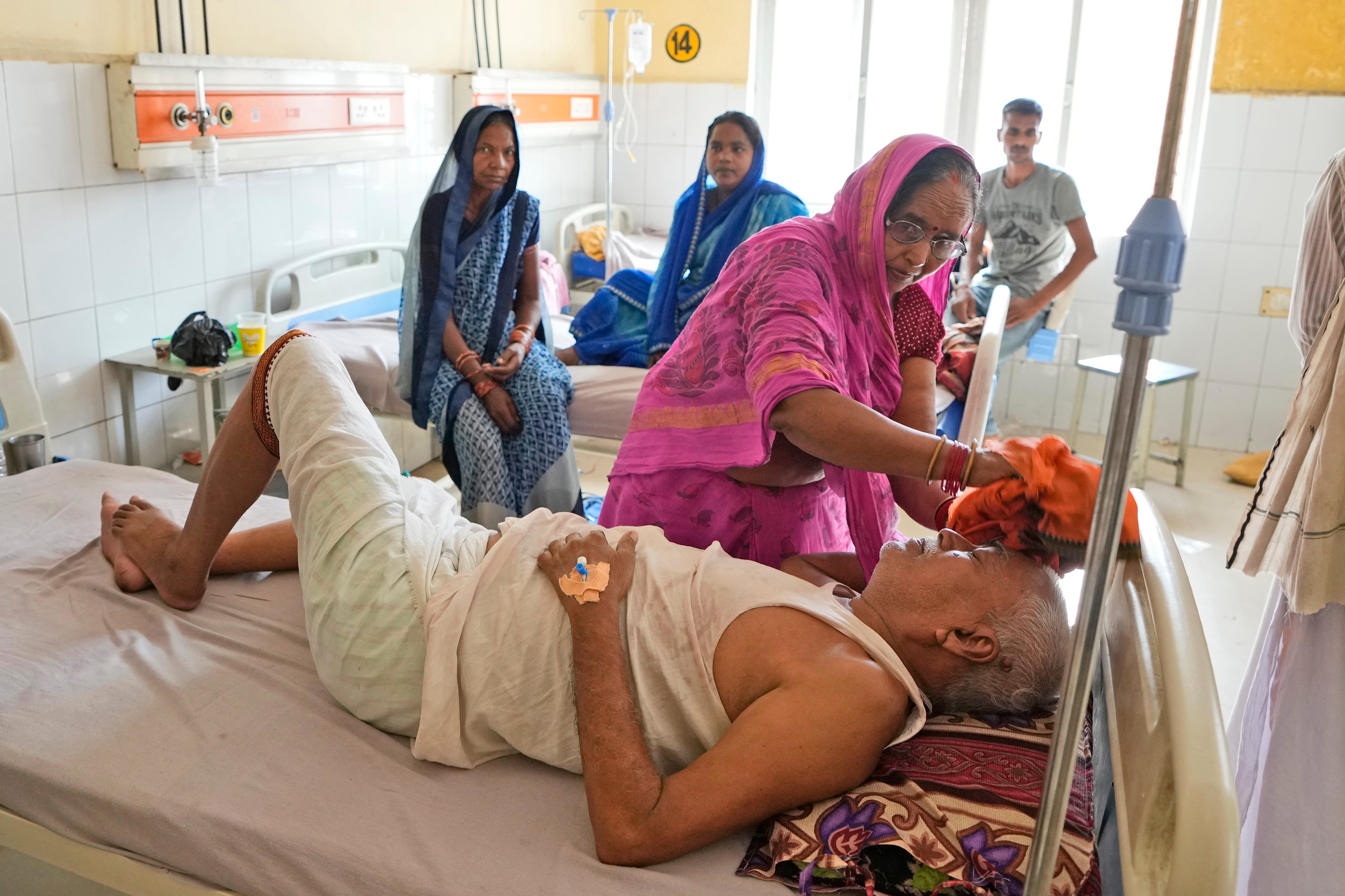 A woman wipes the head of her ailing husband using a wet cloth at the district hospital in Ballia, Uttar Pradesh state