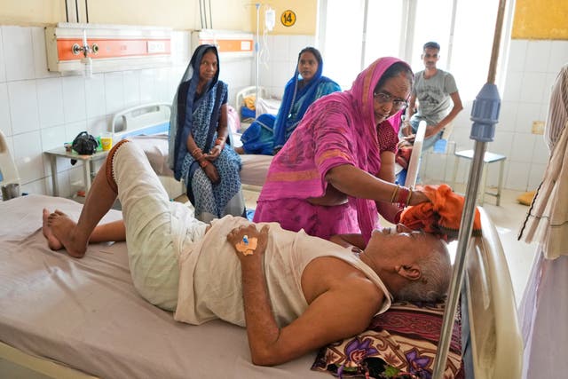 <p>A woman wipes the head of her ailing husband using a wet cloth at the district hospital in Ballia, Uttar Pradesh state</p>