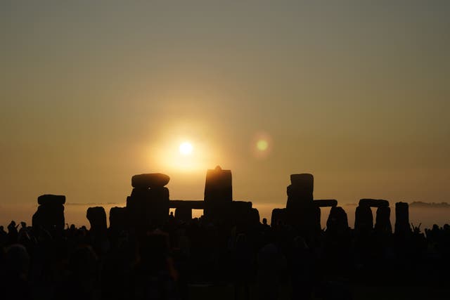 People gather during sunrise as they take part in the Summer Solstice at Stonehenge in Wiltshire (Andrew Matthews/PA)