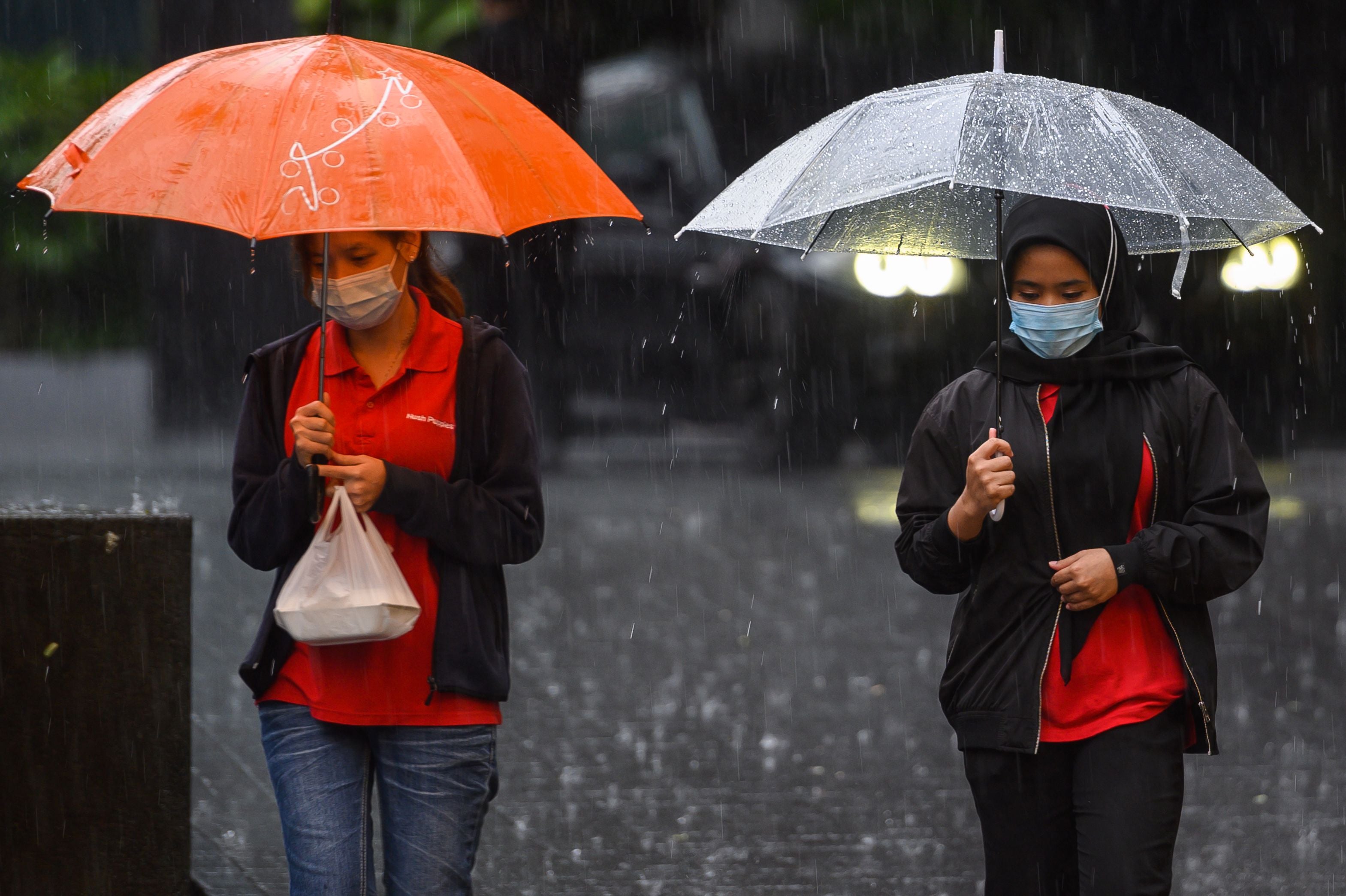 Representational: Women hold umbrellas to shelter from the rain as they walk during a heavy downpour in Malaysia