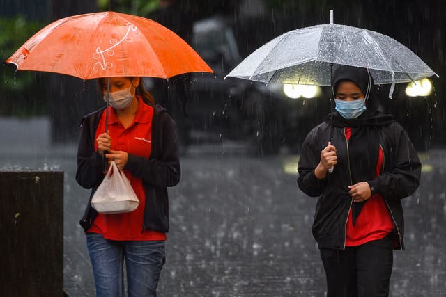 <p>Representational: Women hold umbrellas to shelter from the rain as they walk during a heavy downpour in Malaysia</p>