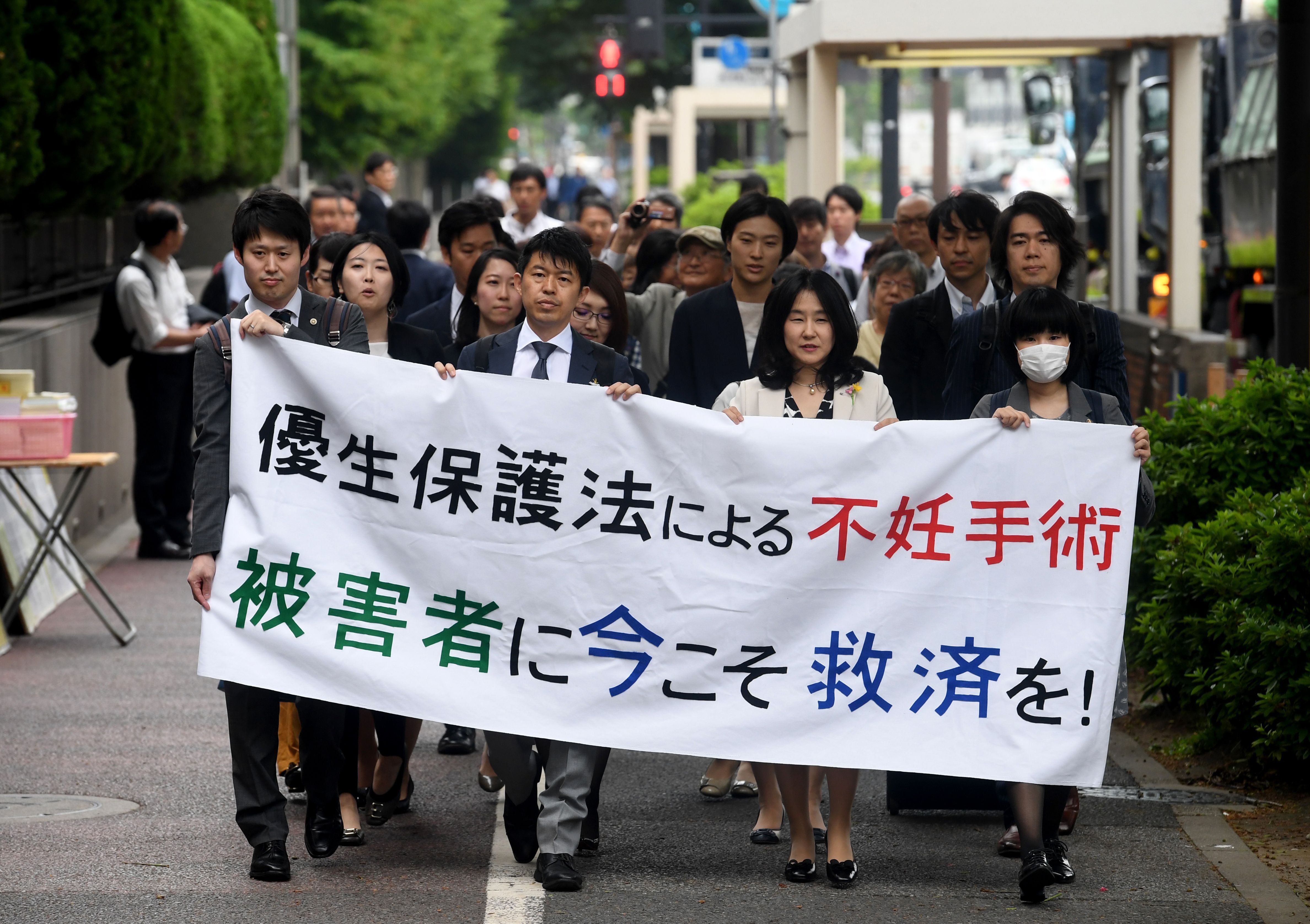 Lawyers and supporters of victims carry a banner saying “Sterilisation under the eugenics law. Relief measures for the victims required now!"