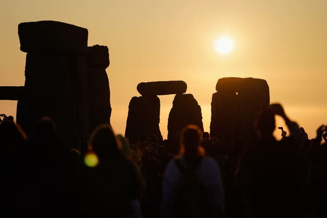 The sun rises behind the stone circle at Stonehenge in Wiltshire where people gathered to mark in the Summer Solstice (Andrew Matthews/PA)