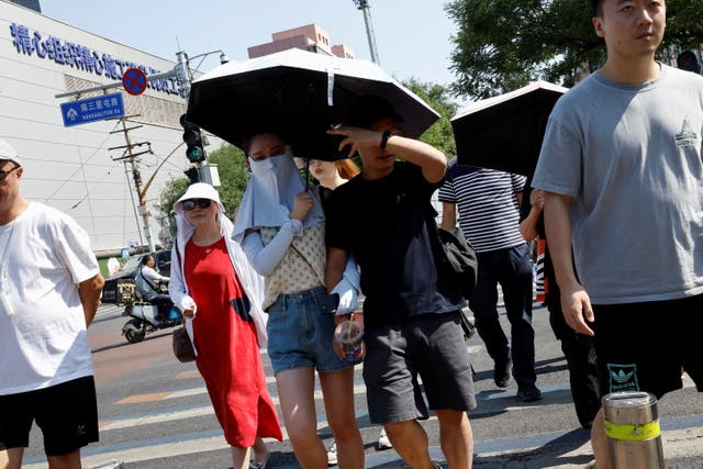 <p>People shield themselves with umbrellas and face masks from the sun amid an orange alert for heatwave in Beijing, China in June 2023. A new study shows little exposure to temperatures of 33C increases risk of stroke </p>