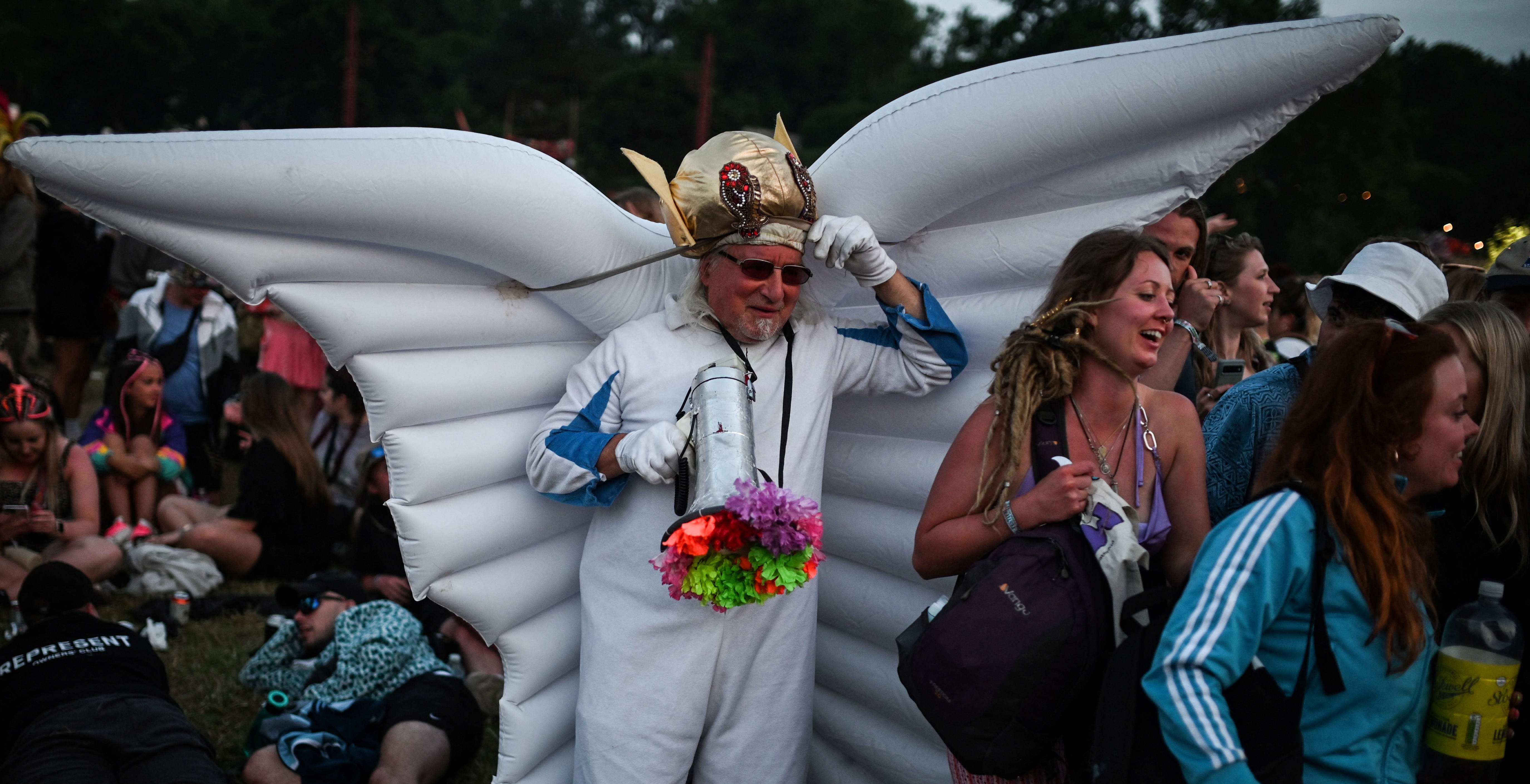 A festival goer wearing inflatable wings walks among the crowd during the first day of the Glastonbury festival