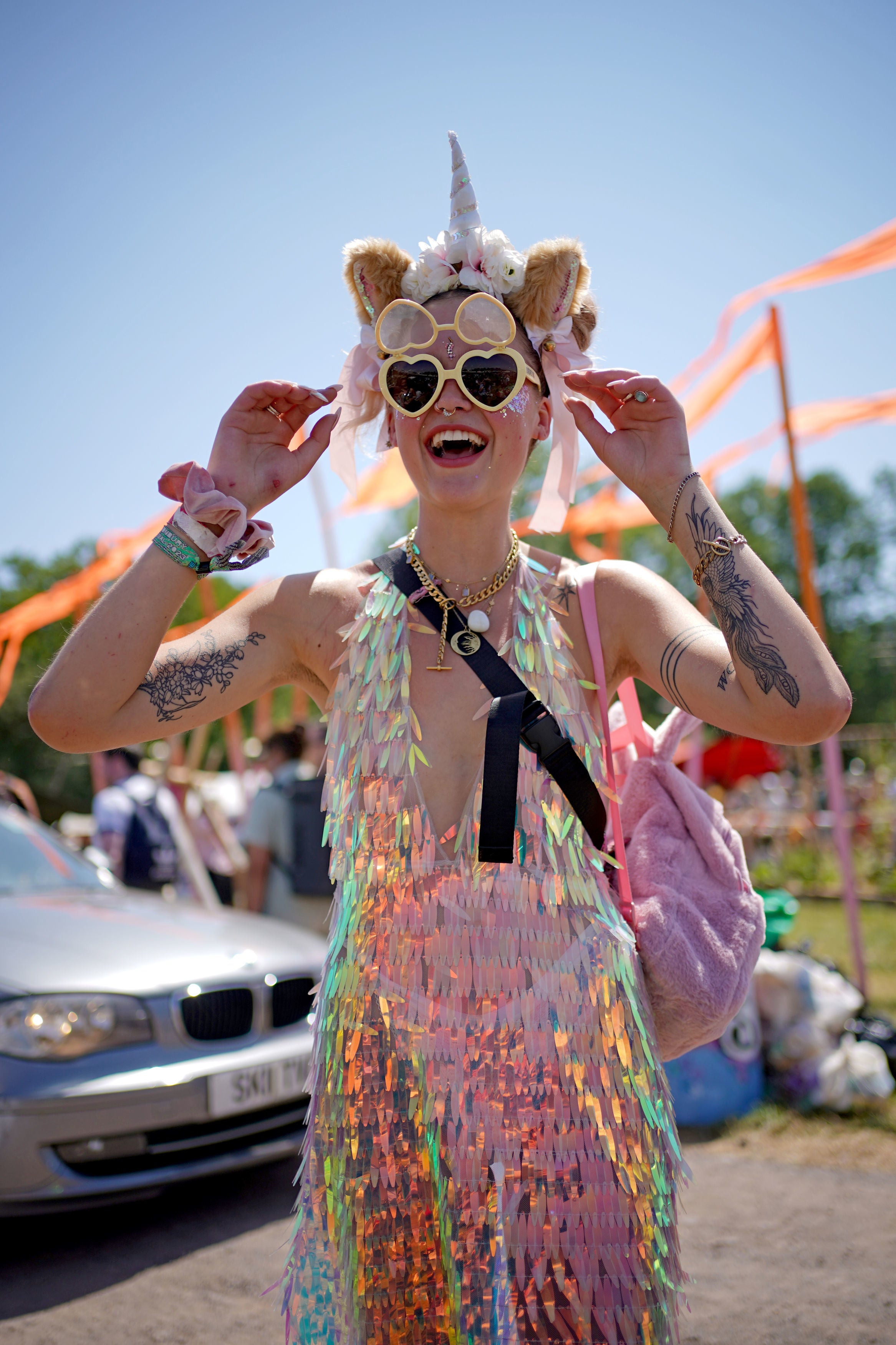 A festivalgoer in a unicorn headband and heart-shaped sunglasses at the Glastonbury Festival