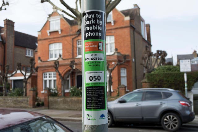 A notice with instructions on how to use a mobile to pay for parking is displayed on a lamppost in Putney, south-west London (Alamy/PA)